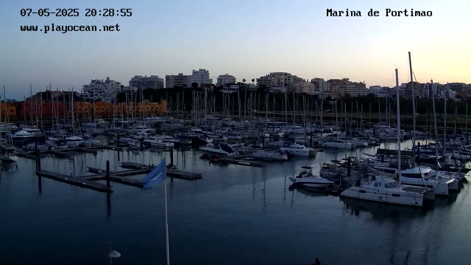 A marina filled with numerous boats and yachts at dusk, under a clear sky.