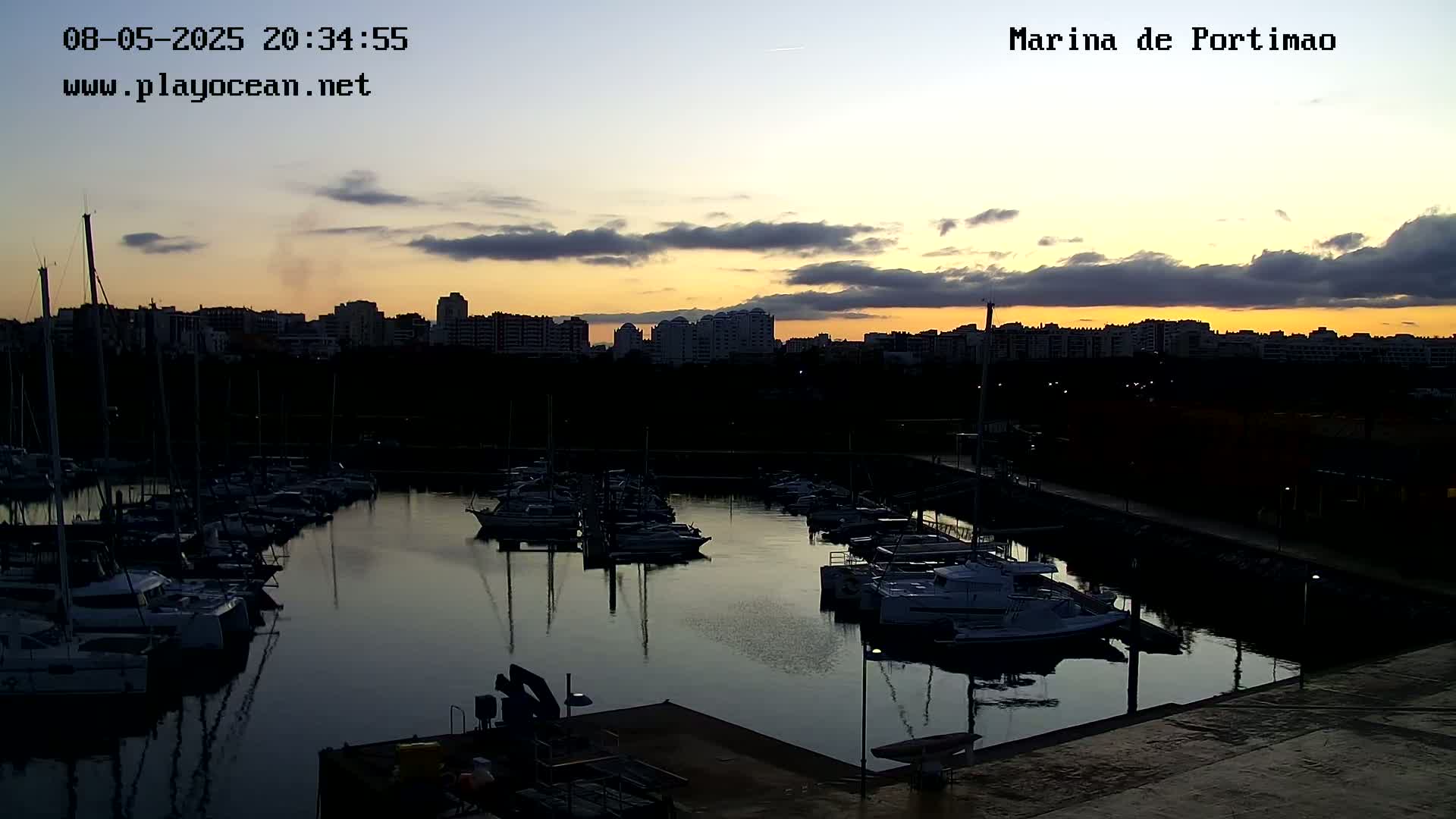 A marina filled with boats at sunset, under a partly cloudy sky.