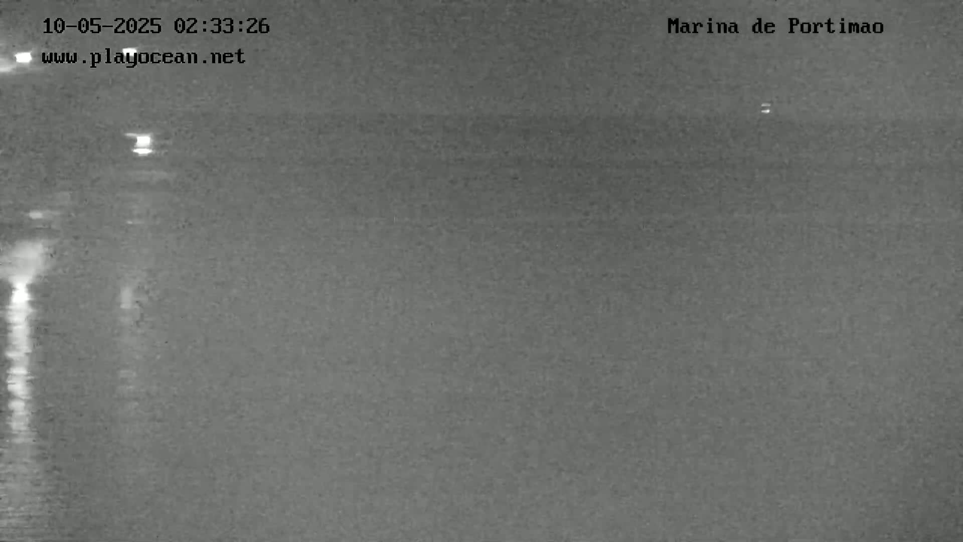A nighttime, low-light image shows a dark body of water with minimal wave action.