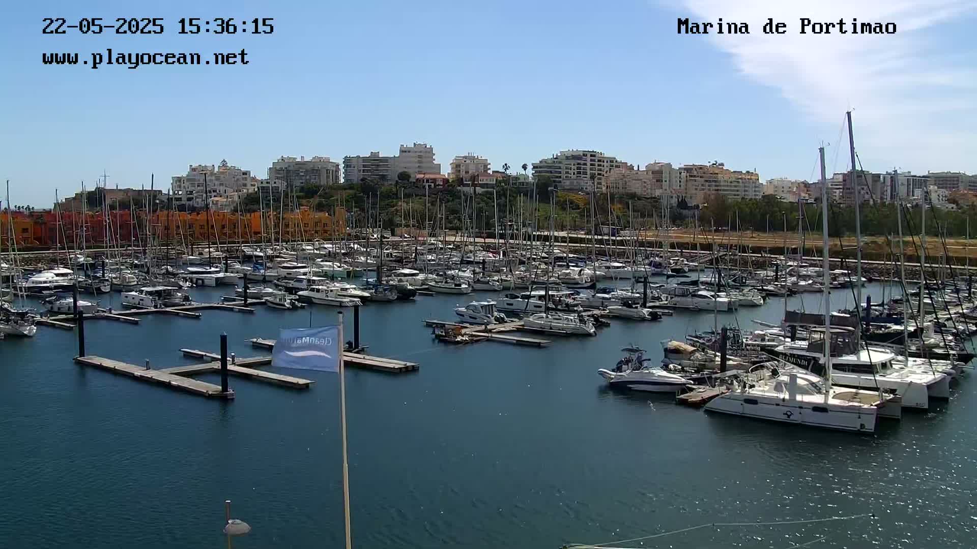 A marina filled with numerous sailboats and motorboats on a sunny day.