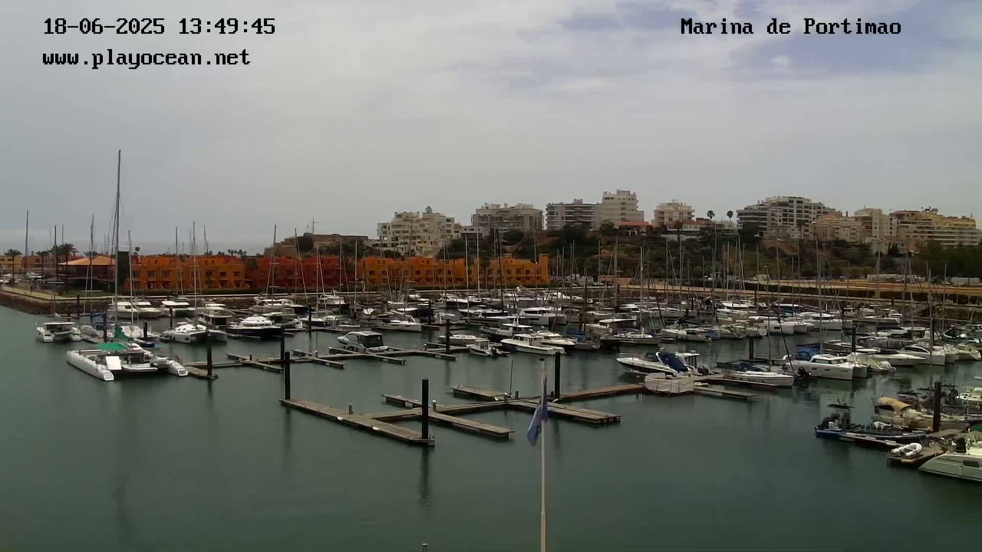 A marina filled with numerous boats and yachts is seen under an overcast sky.