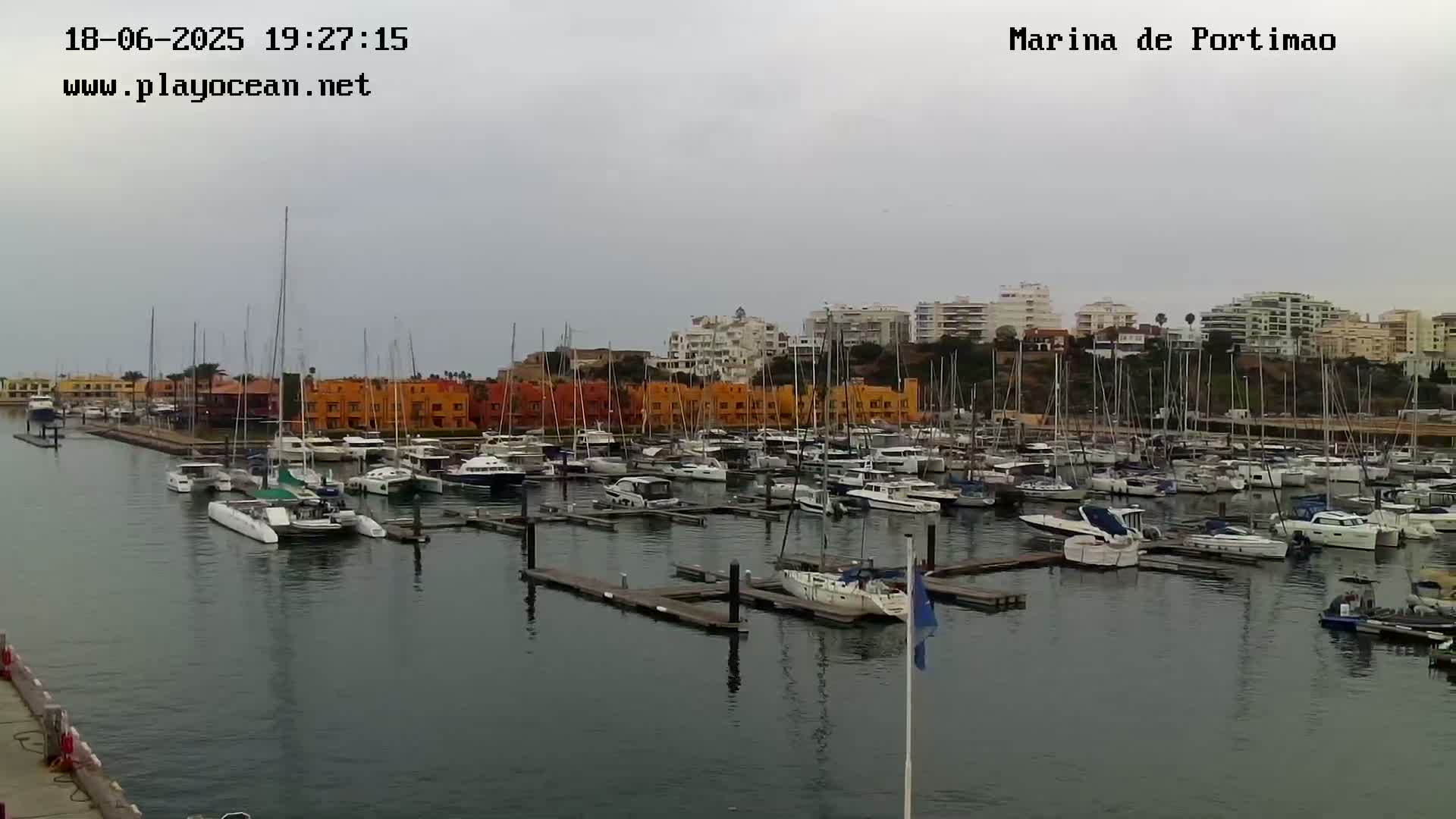 A marina filled with numerous boats and yachts under an overcast sky.
