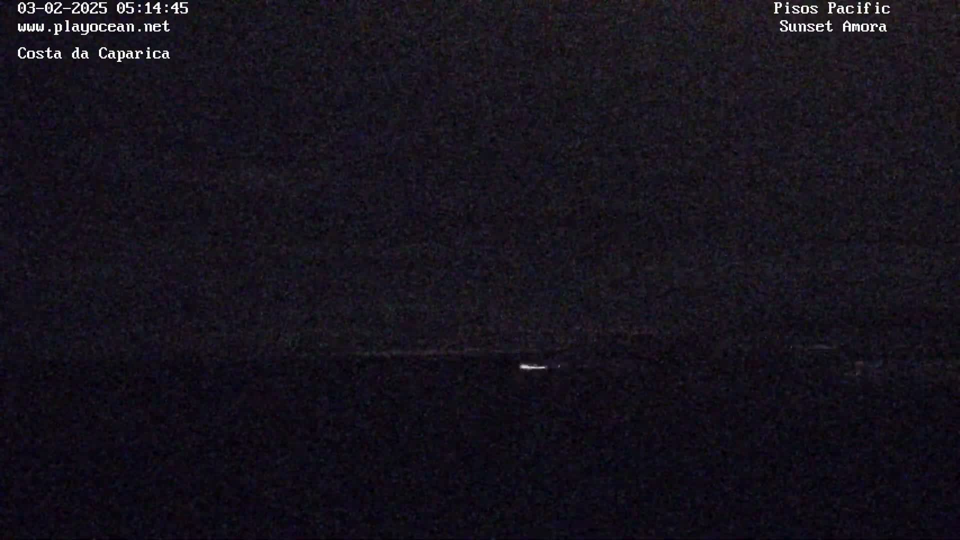 A dark, nighttime scene shows a very faint horizon line with a small light visible in the distance.