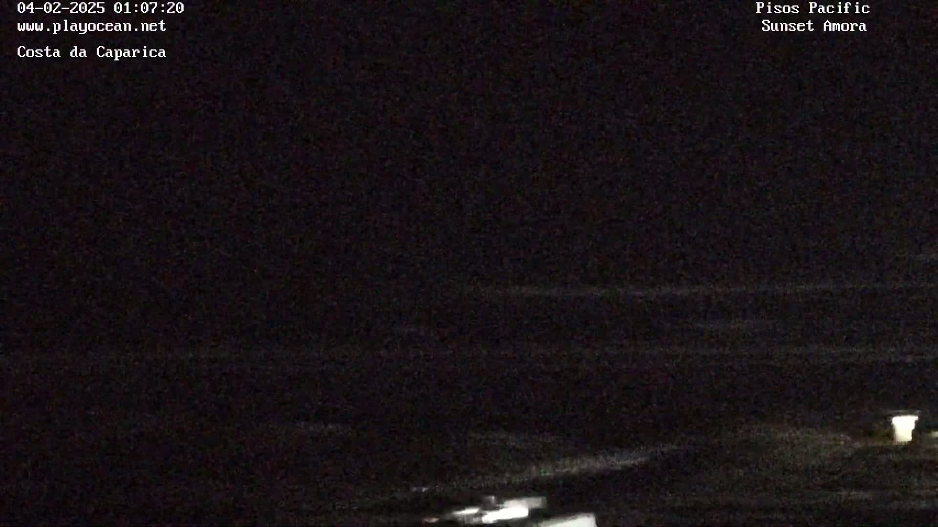 A dark, nighttime view of the ocean with faint waves visible.