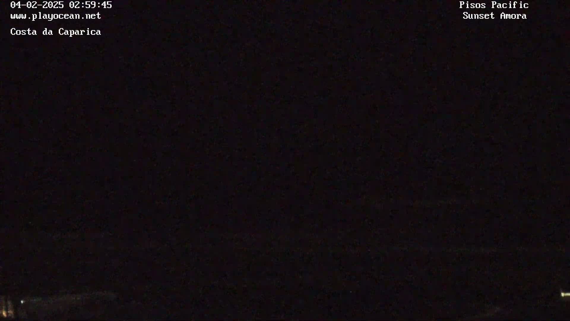 A nighttime, dark image shows a mostly black scene with a few faint lights visible near the bottom.