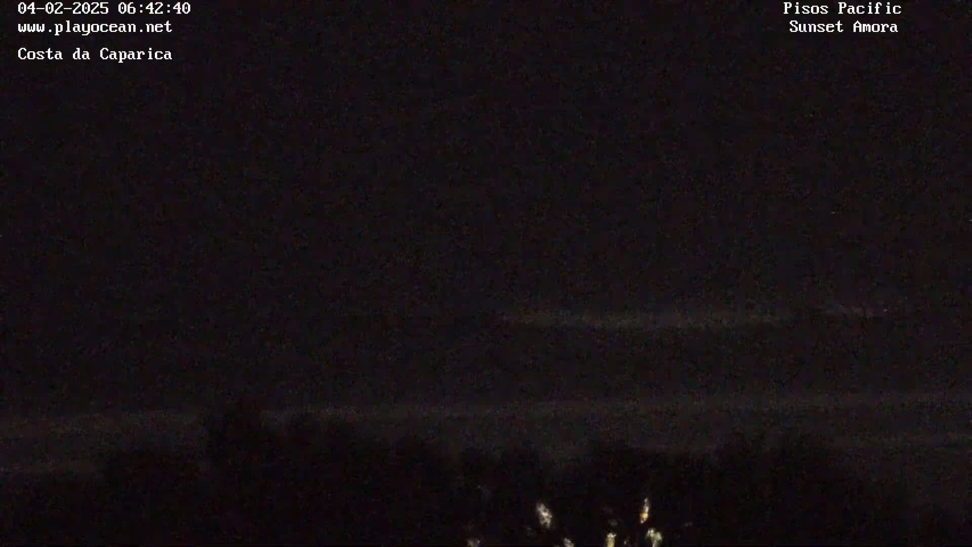 A dark, nighttime scene shows a faint horizon line with a few lights visible in the distance.