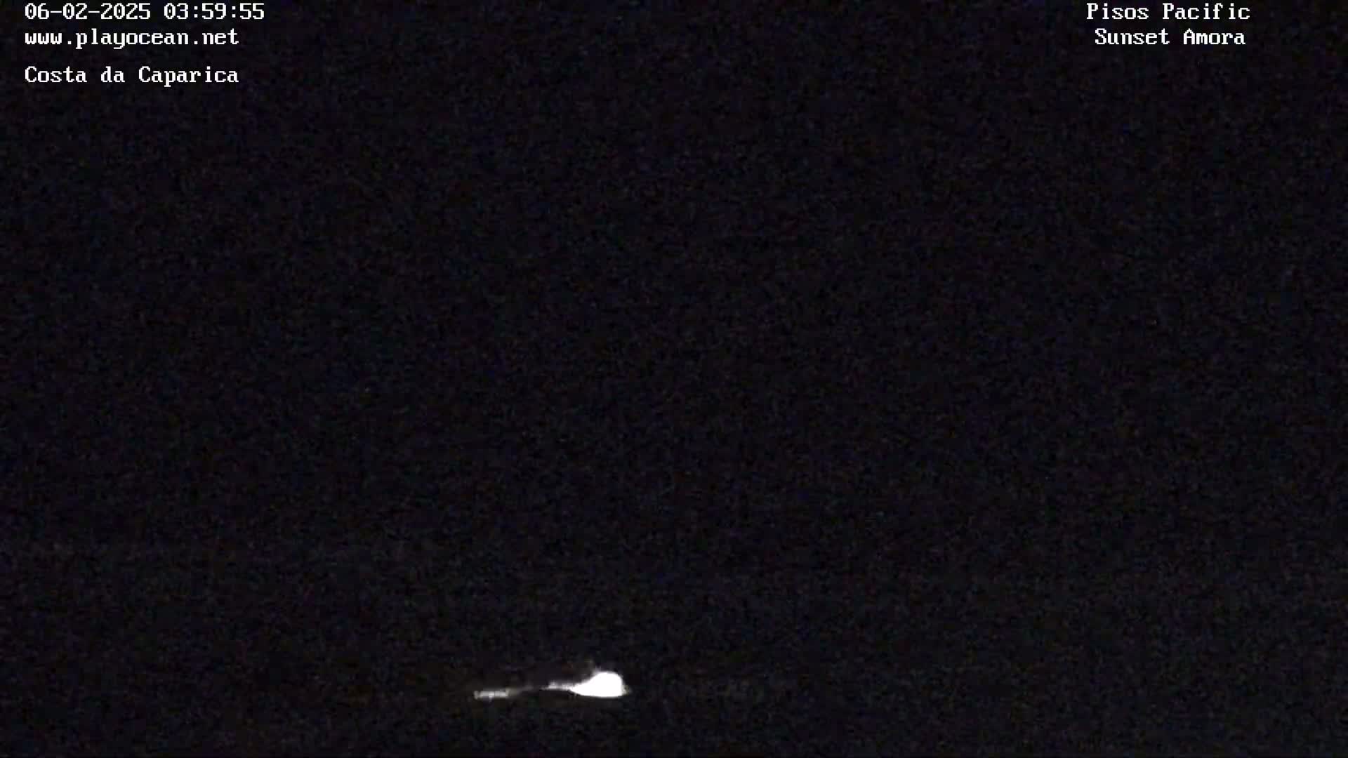 A low-light nighttime image shows a faint, bright glow near the bottom of the frame against a completely dark background.