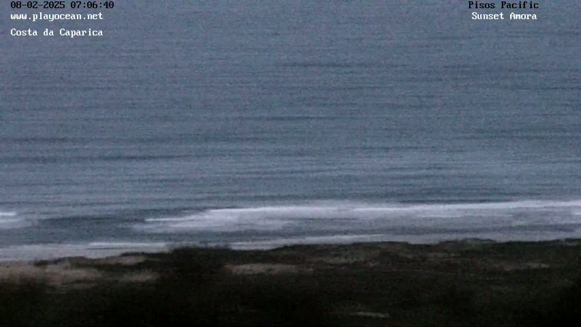 A dark, overcast sky hangs over a calm ocean meeting a dark shoreline.