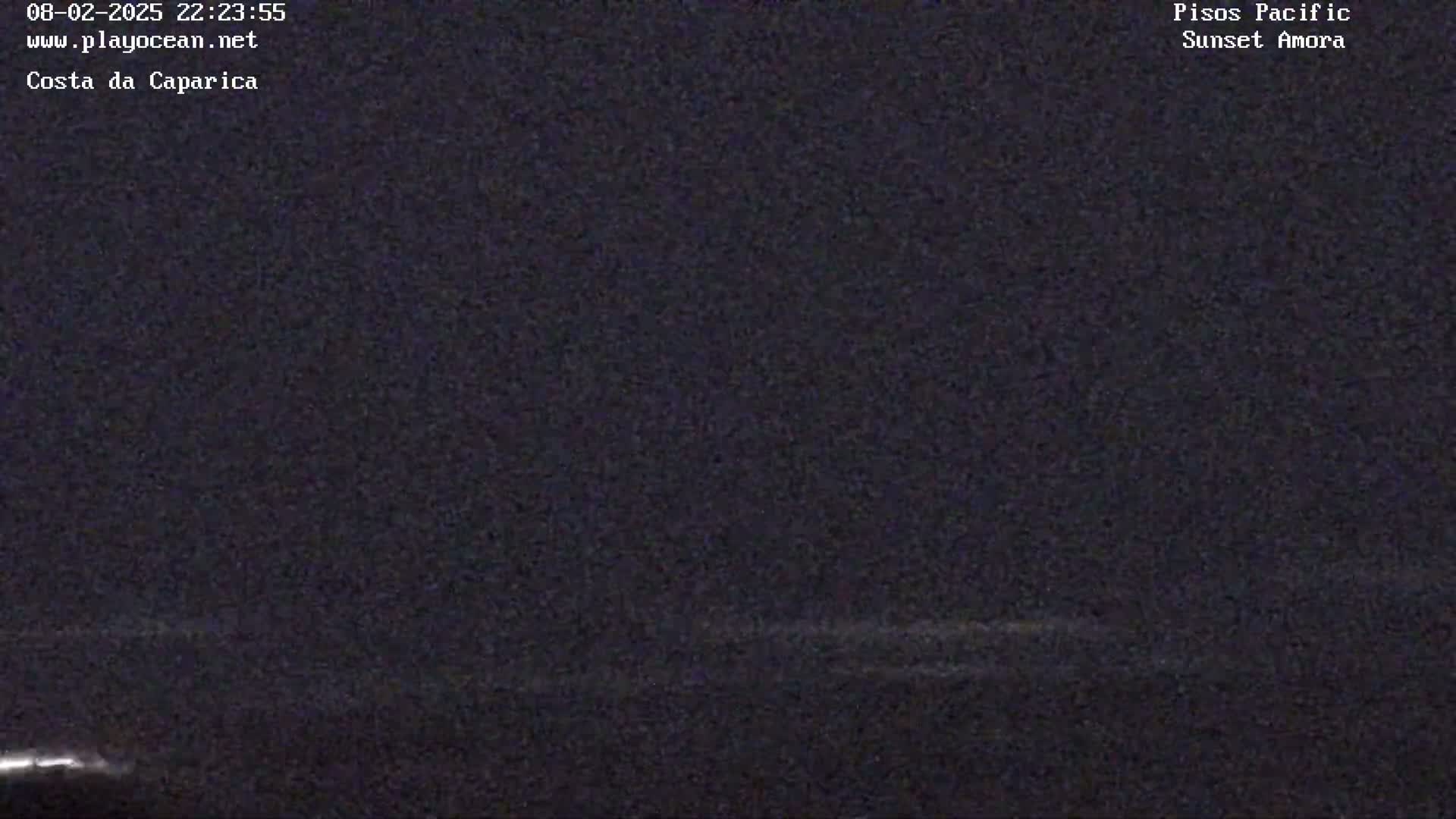 A dark, nighttime image shows a mostly obscured view of the ocean under a cloudy sky.