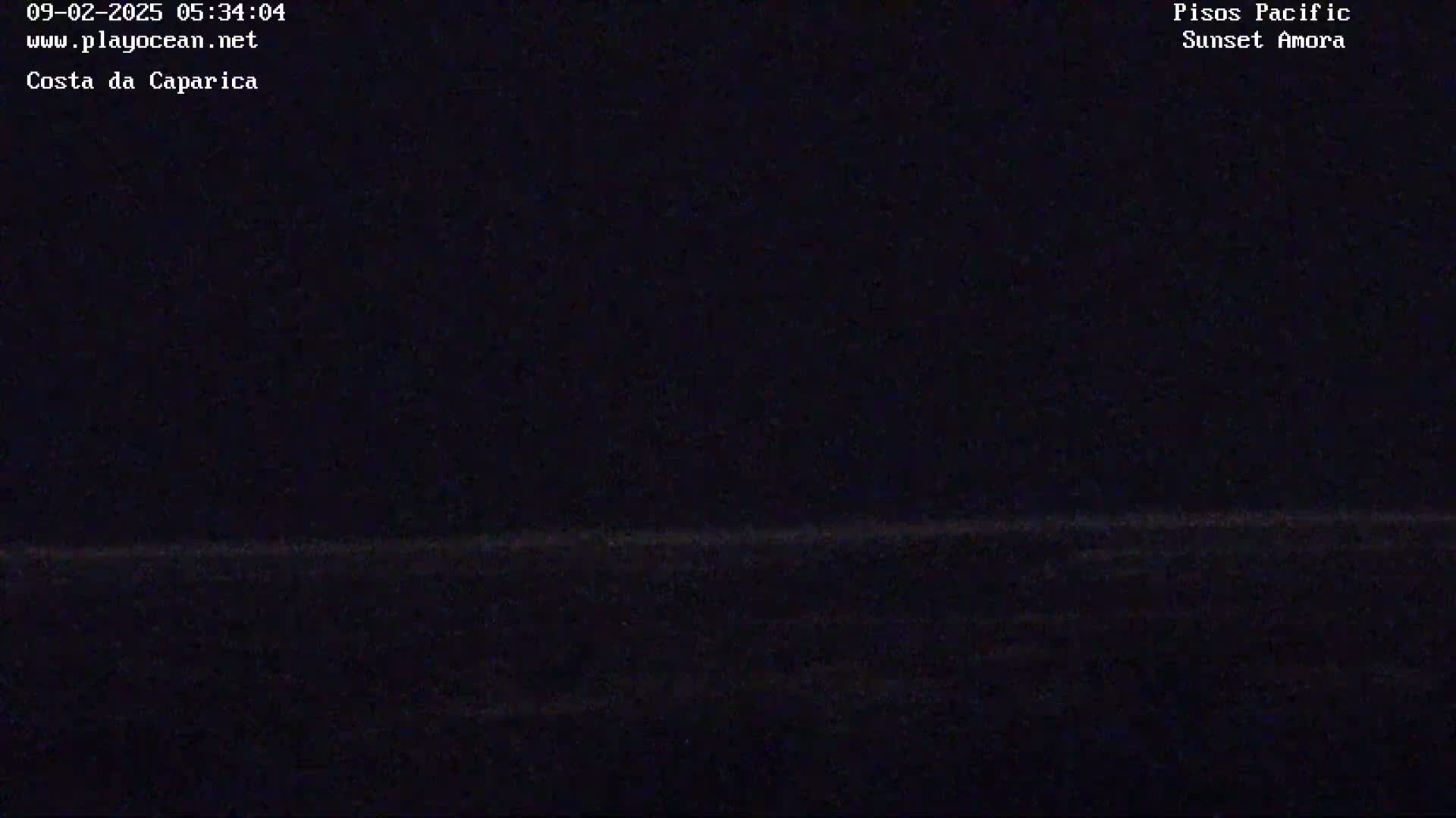 A dark, nighttime image shows a barely visible horizon line separating a dark sky from a dark body of water.
