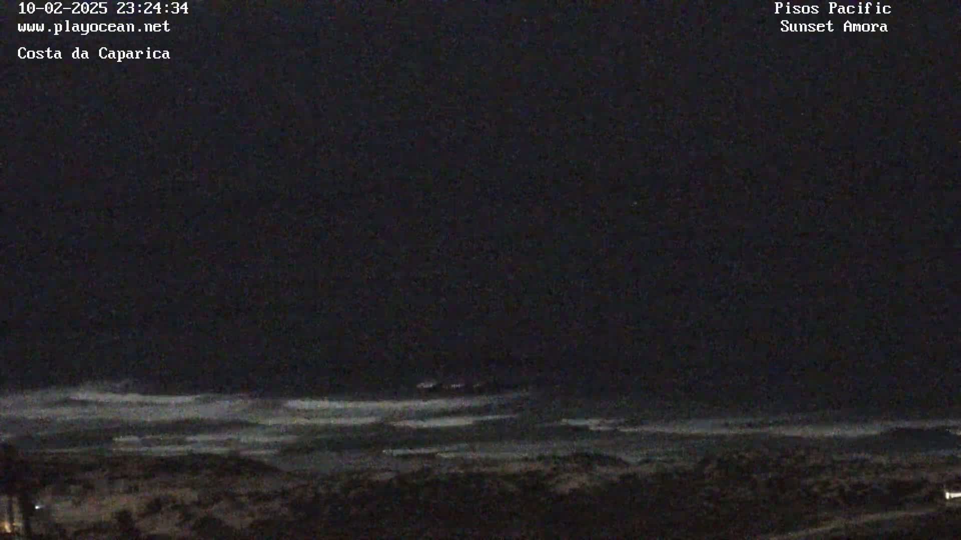 A dark, nighttime beach scene shows a wavy ocean under a mostly clear sky.