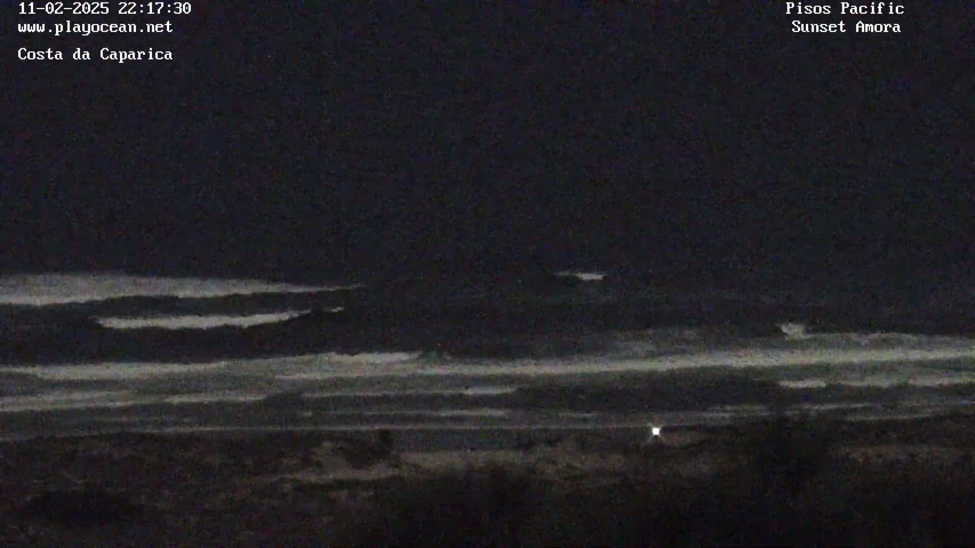 A dark nighttime coastal scene shows dark waves on the ocean under a black sky.
