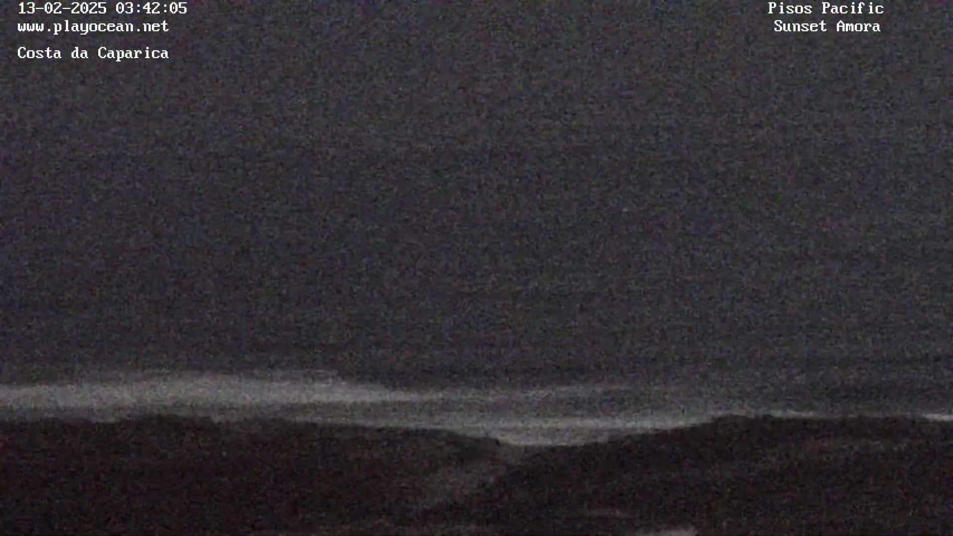 A dark, nighttime coastal scene shows a faint, light horizon line above a dark landmass under a mostly clear sky.