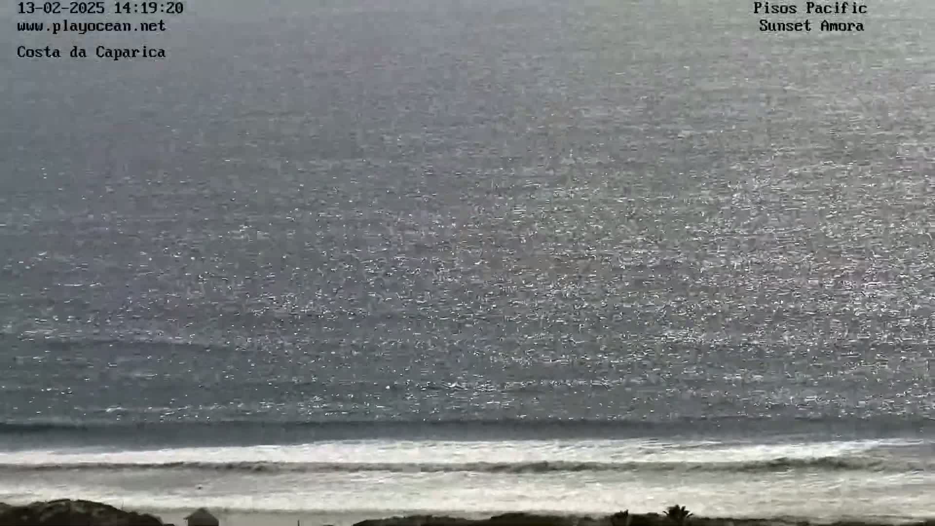 A gray, somewhat overcast day shows a wide expanse of dark, choppy ocean waves reaching a sandy shoreline.