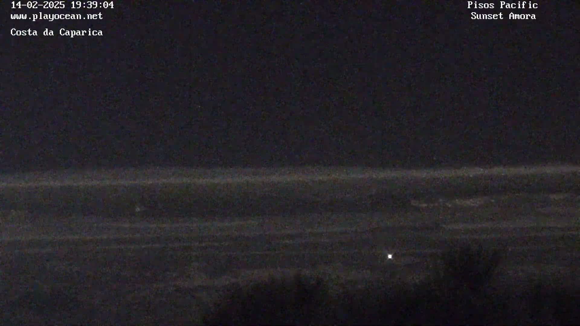 A nighttime long shot shows a dark ocean meeting a dark shoreline under a clear, dark sky.