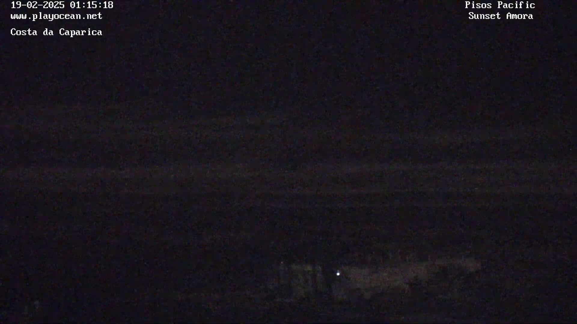 A dark nighttime scene shows a dimly lit shoreline with faint horizontal lines suggesting water under a dark sky.