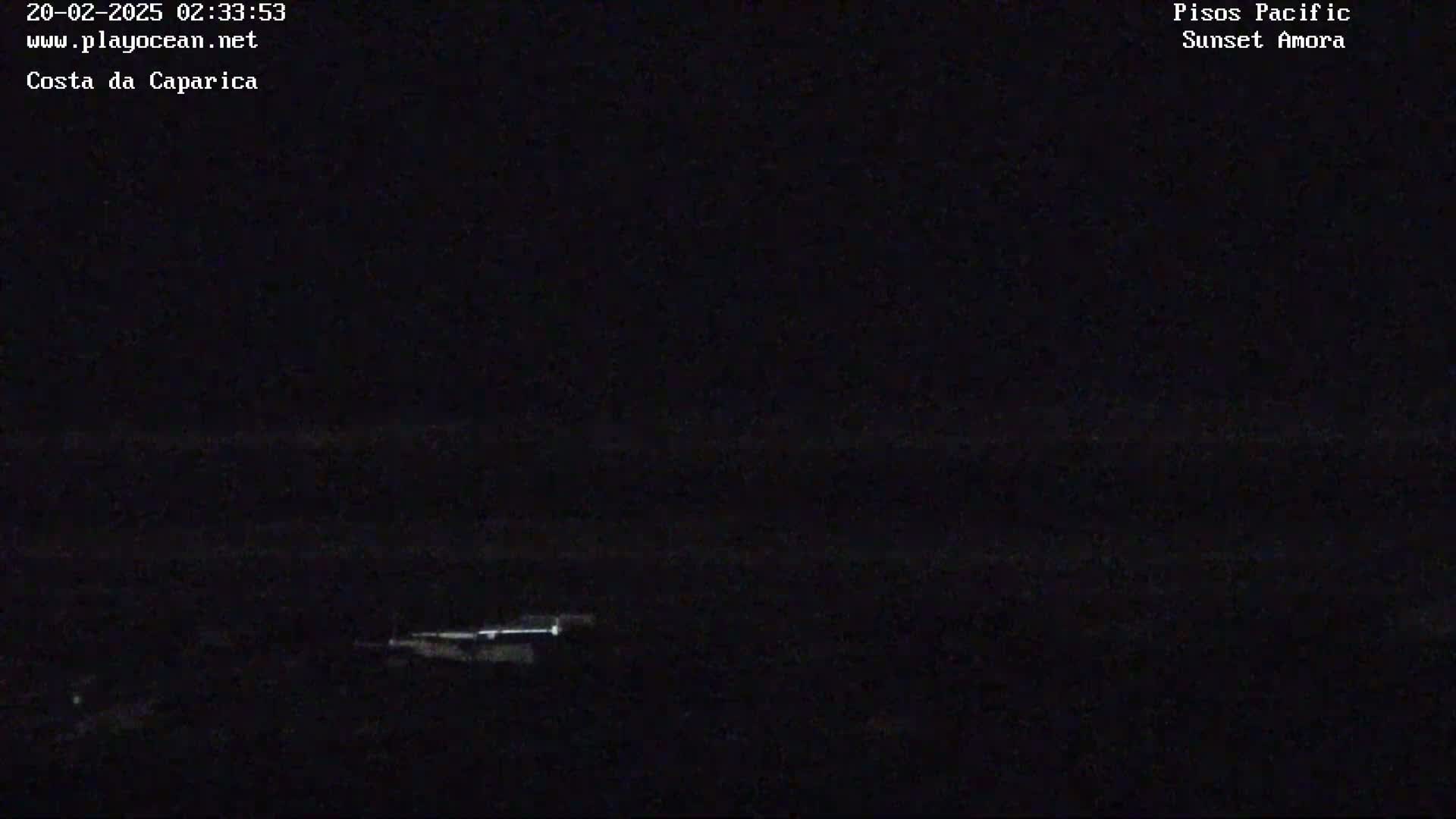 A dark, nighttime scene shows a dimly lit shoreline with a faint horizon.