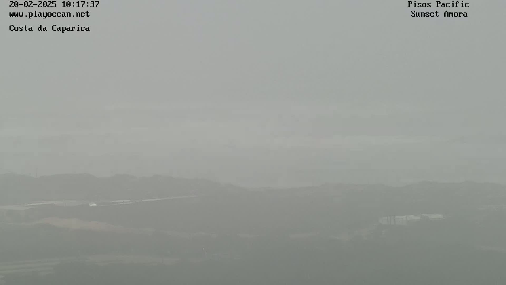 A hazy, overcast view shows low-lying hills and a flat expanse of land in the distance.