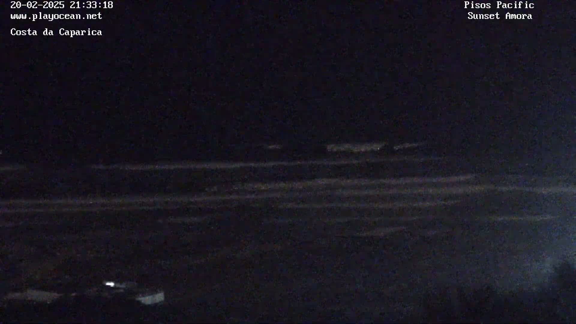 A dark, nighttime view of a wavy ocean under a clear sky.