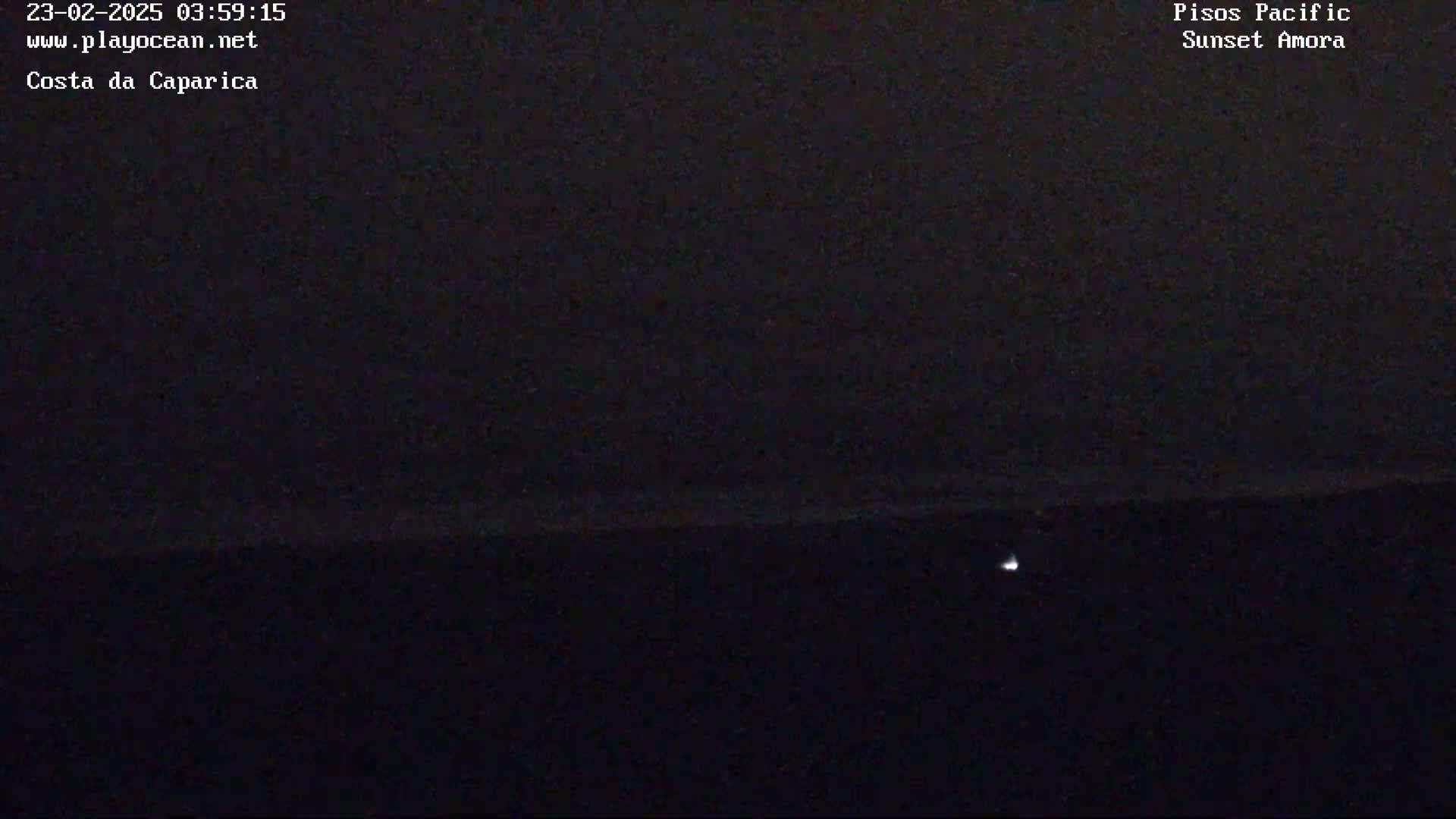 A dark, nighttime scene shows a faint light on a dark horizon.
