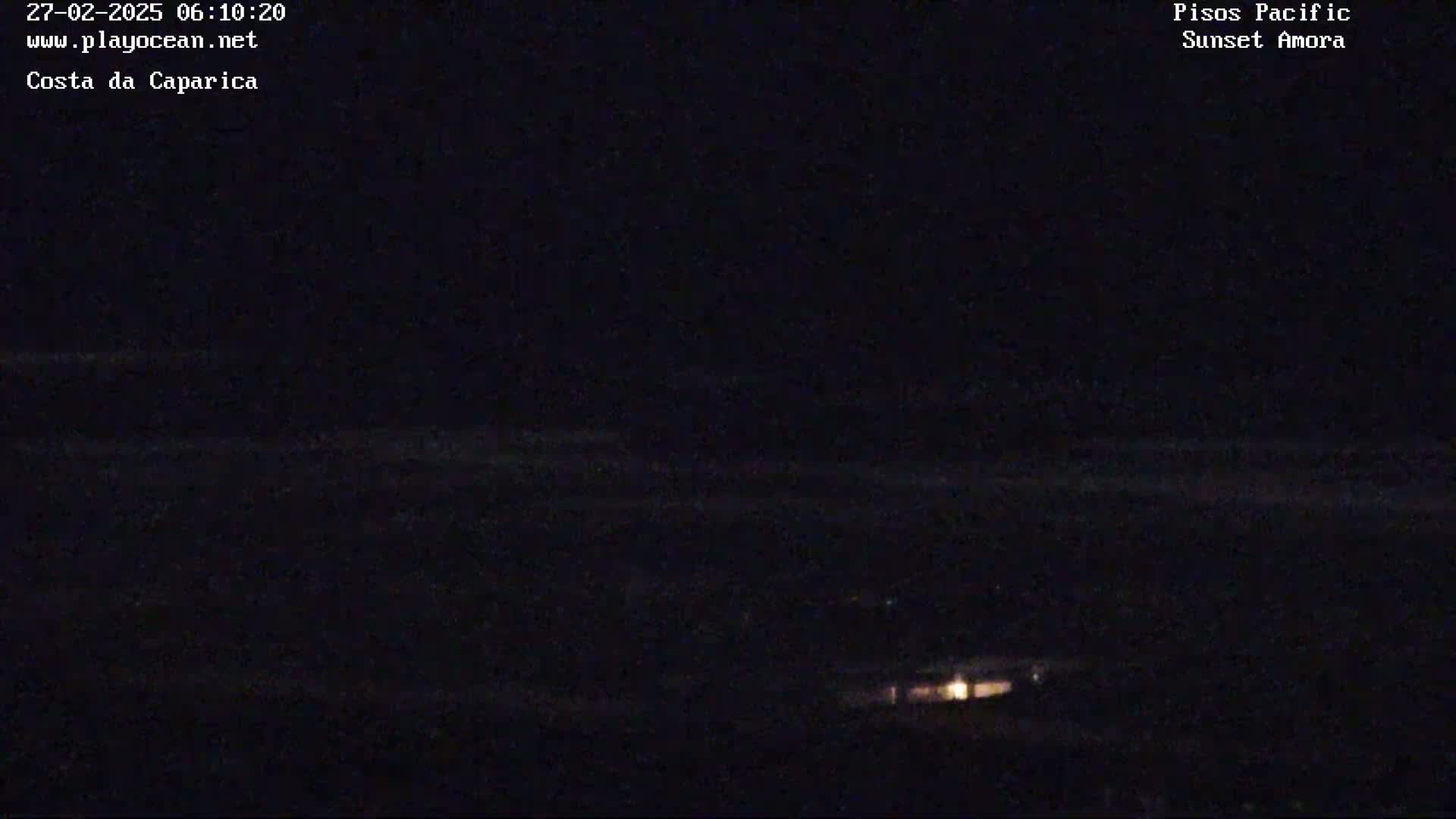 A dark, nighttime scene shows a dimly lit structure in the lower center with a dark horizon and faint horizontal streaks in the sky.