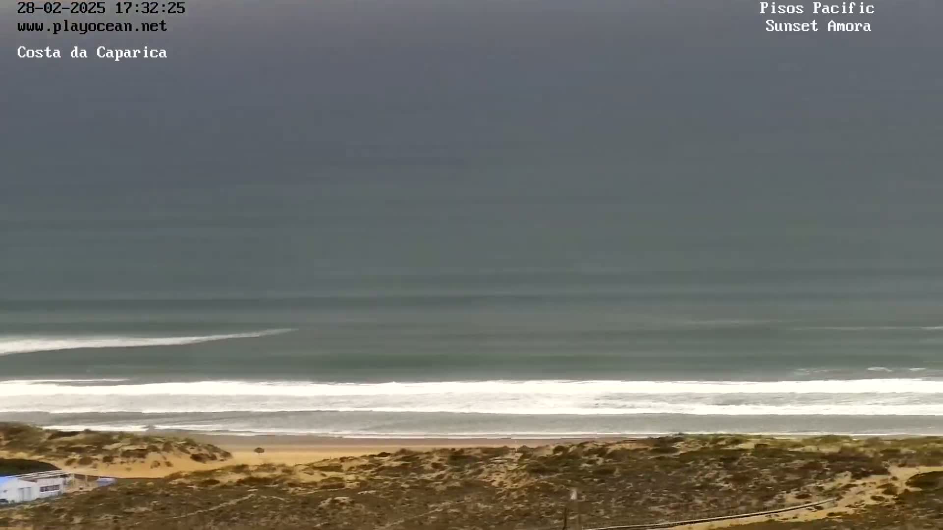 An overcast sky overlooks a beach with waves rolling onto the shore.