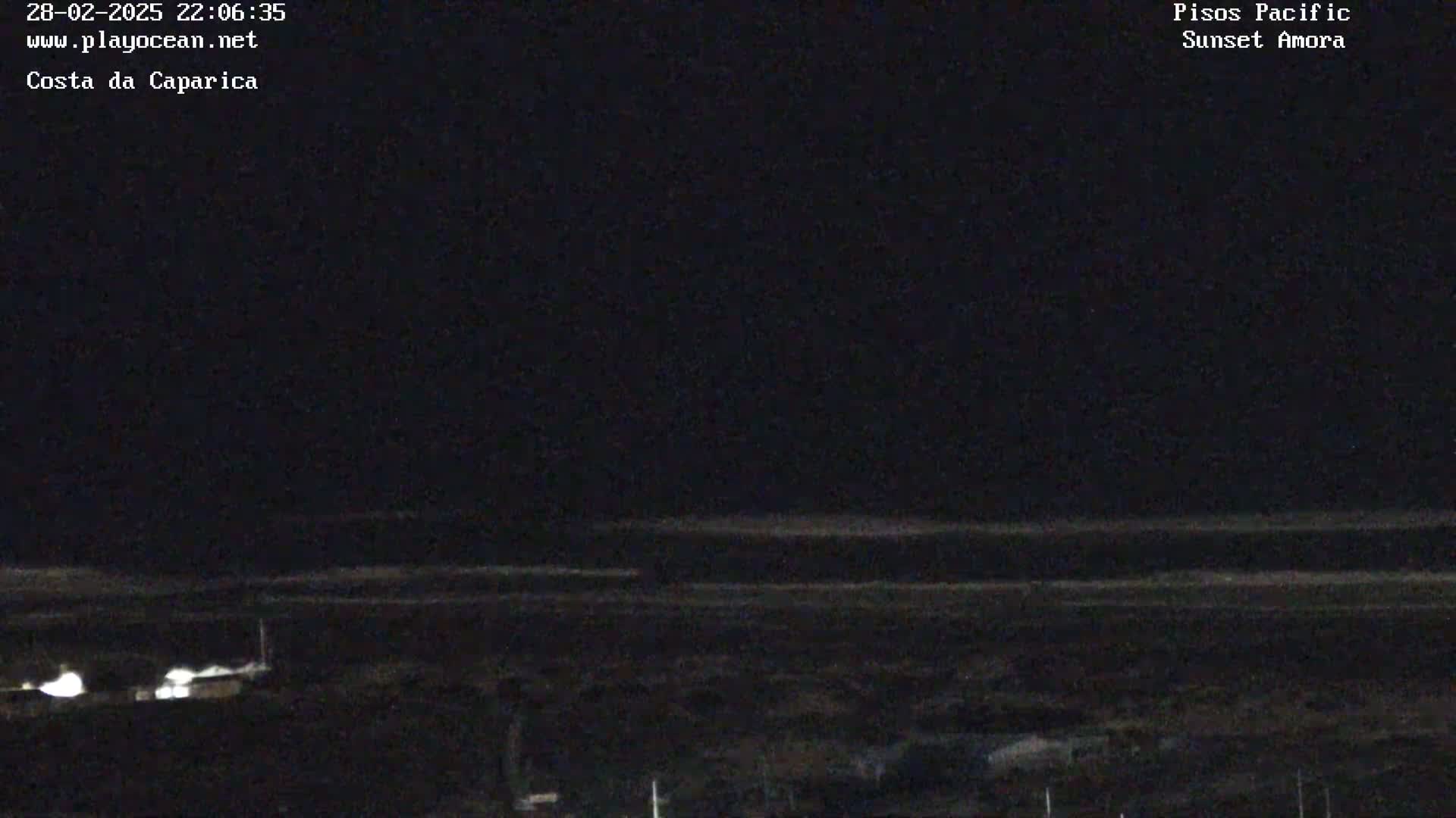 A nighttime view of a dark beach and ocean under a clear, dark sky.