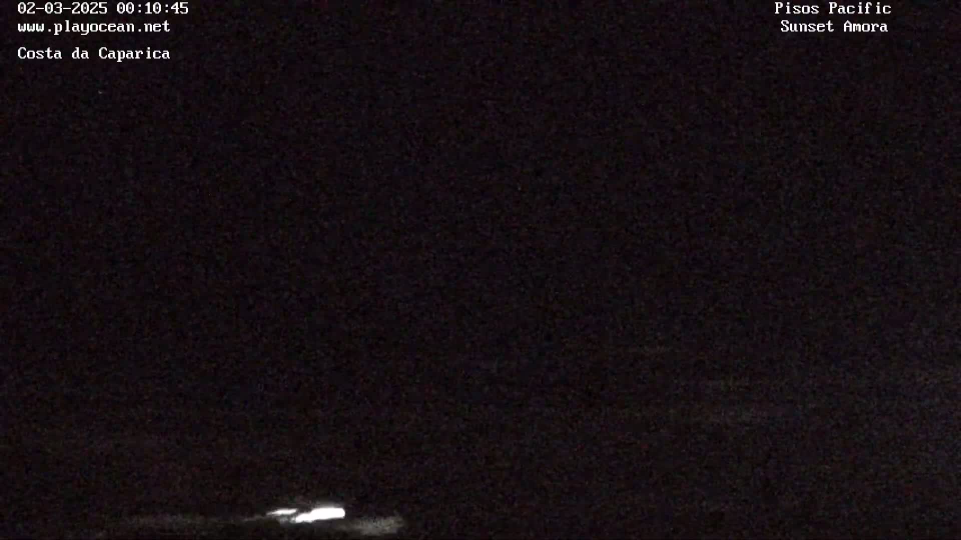 A nighttime, low-light outdoor image shows a dark horizon with a faint, blurry light source near the bottom.