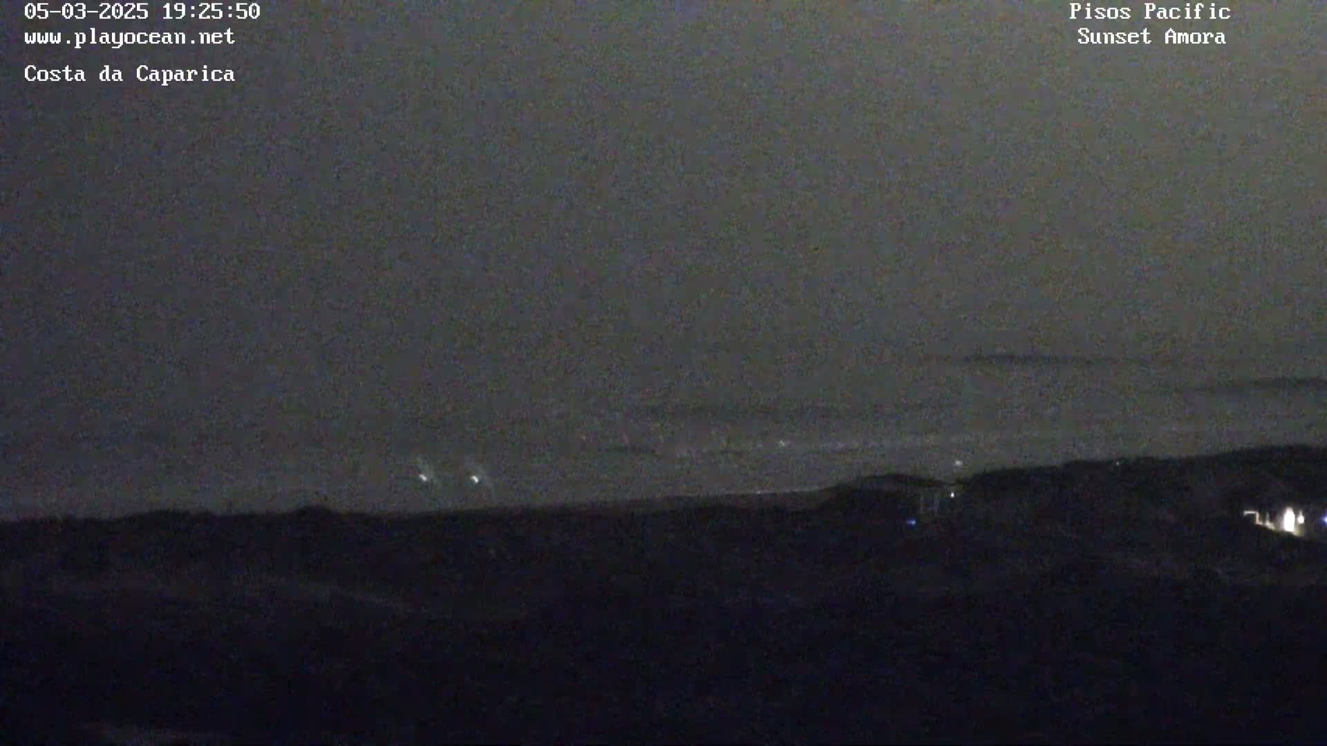 A nighttime long shot shows a dark ocean under a mostly cloudy sky, with a dark shoreline in the foreground.