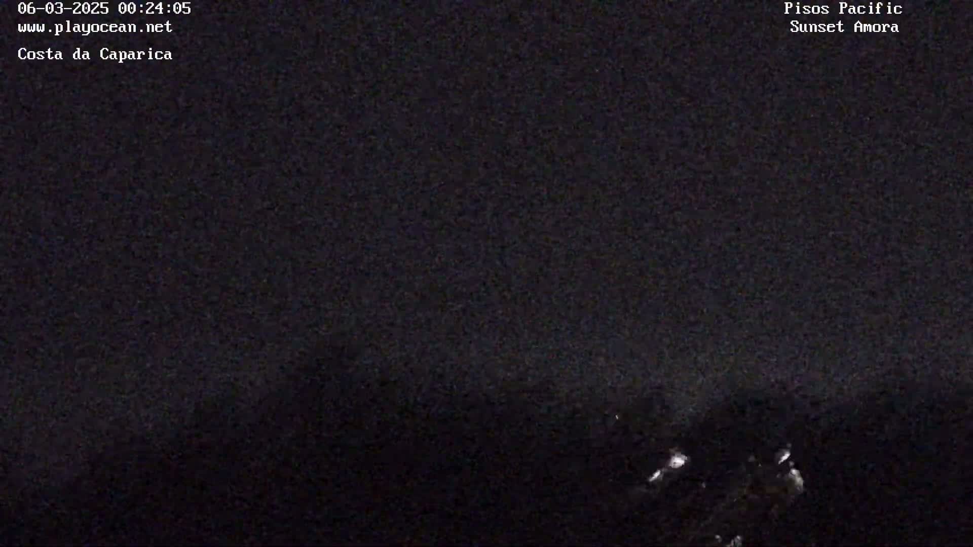 A nighttime, dark, and blurry outdoor image shows a low-lit scene with some faint lights in the bottom right corner.