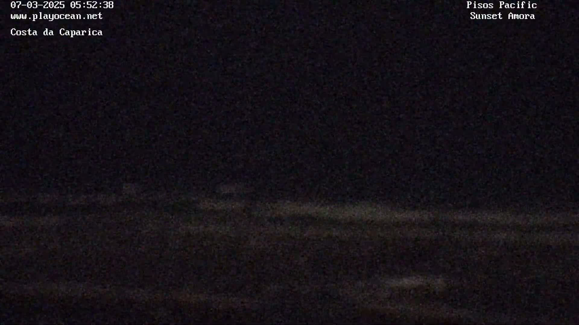 A dark, nighttime image shows a mostly black ocean with faint, barely visible waves under a clear, dark sky.