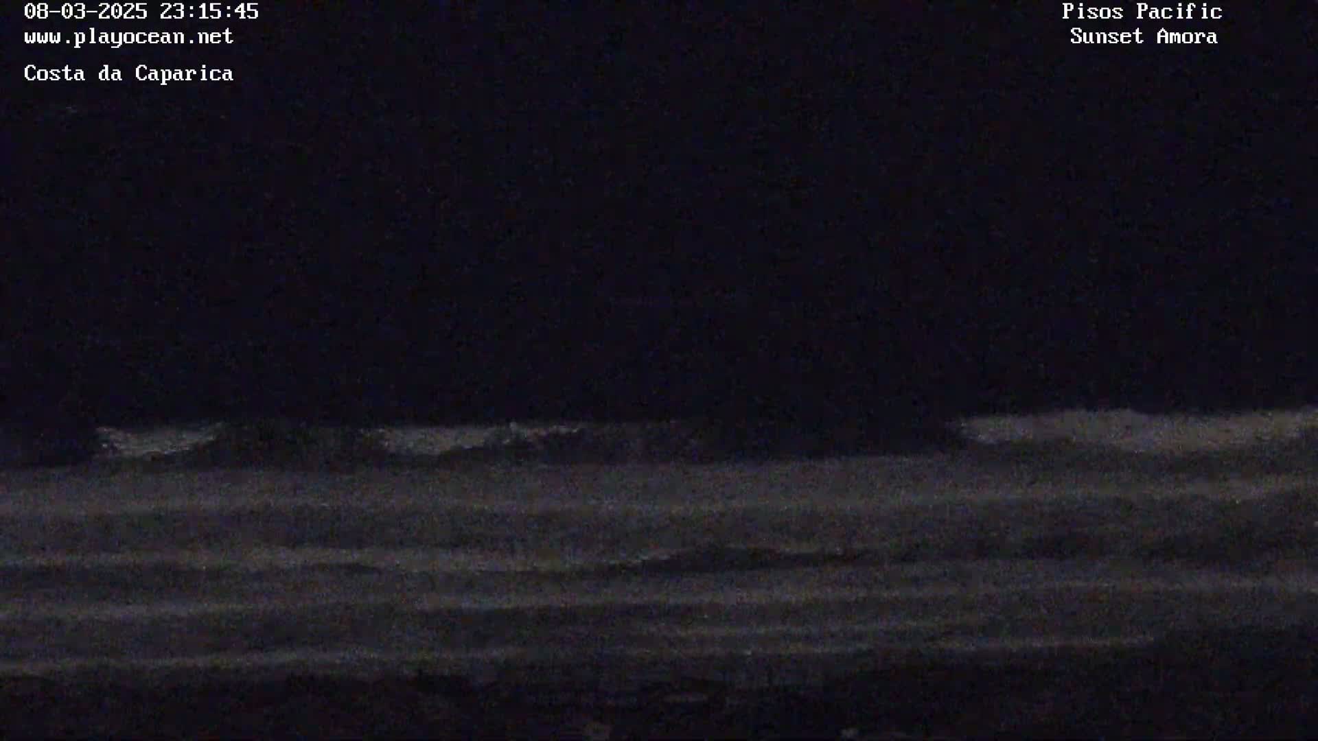 A dark, nighttime view of a wavy ocean under a clear sky.