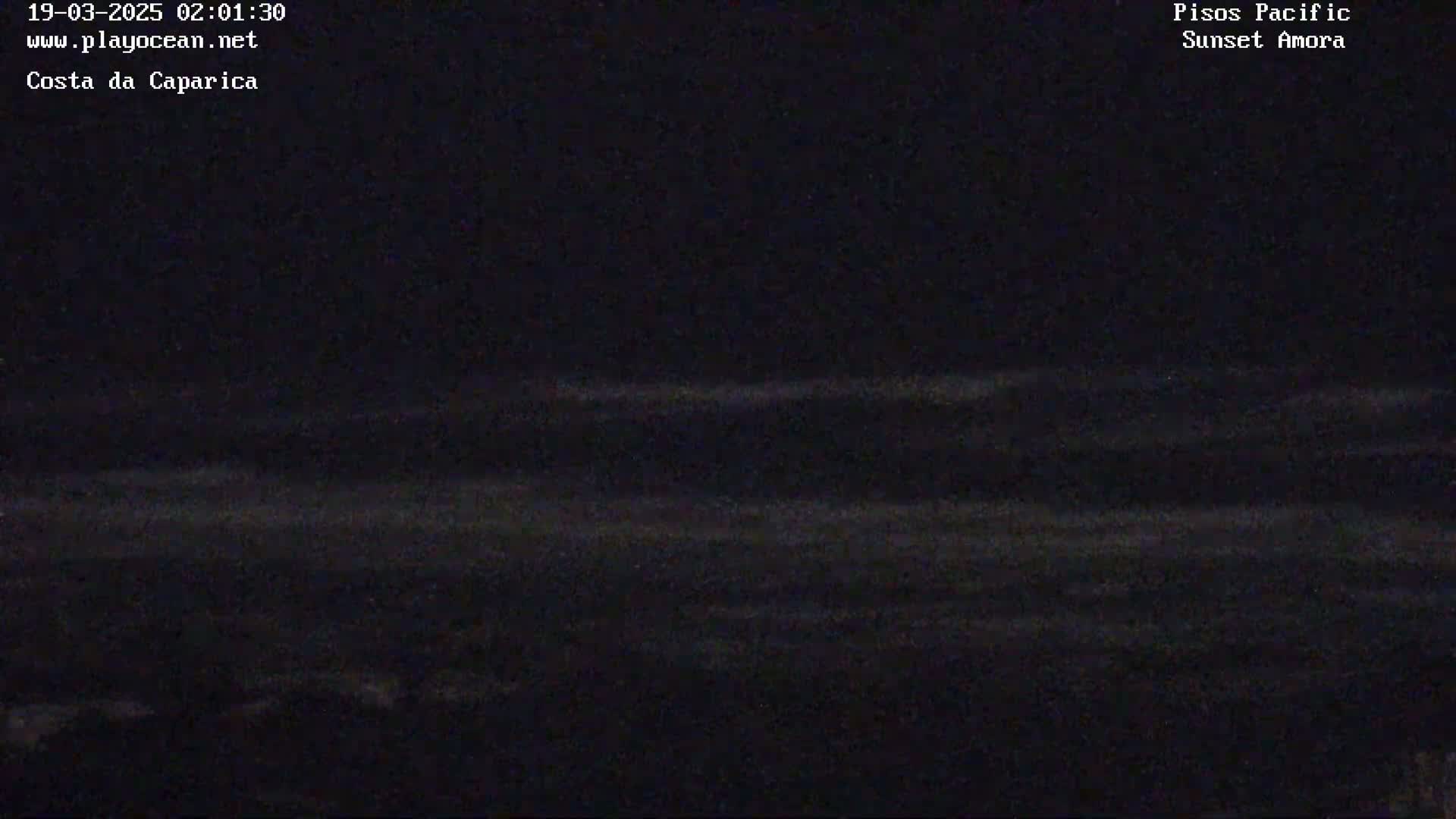 A dark, nighttime view of a body of water shows faintly visible waves under a clear, starless sky.