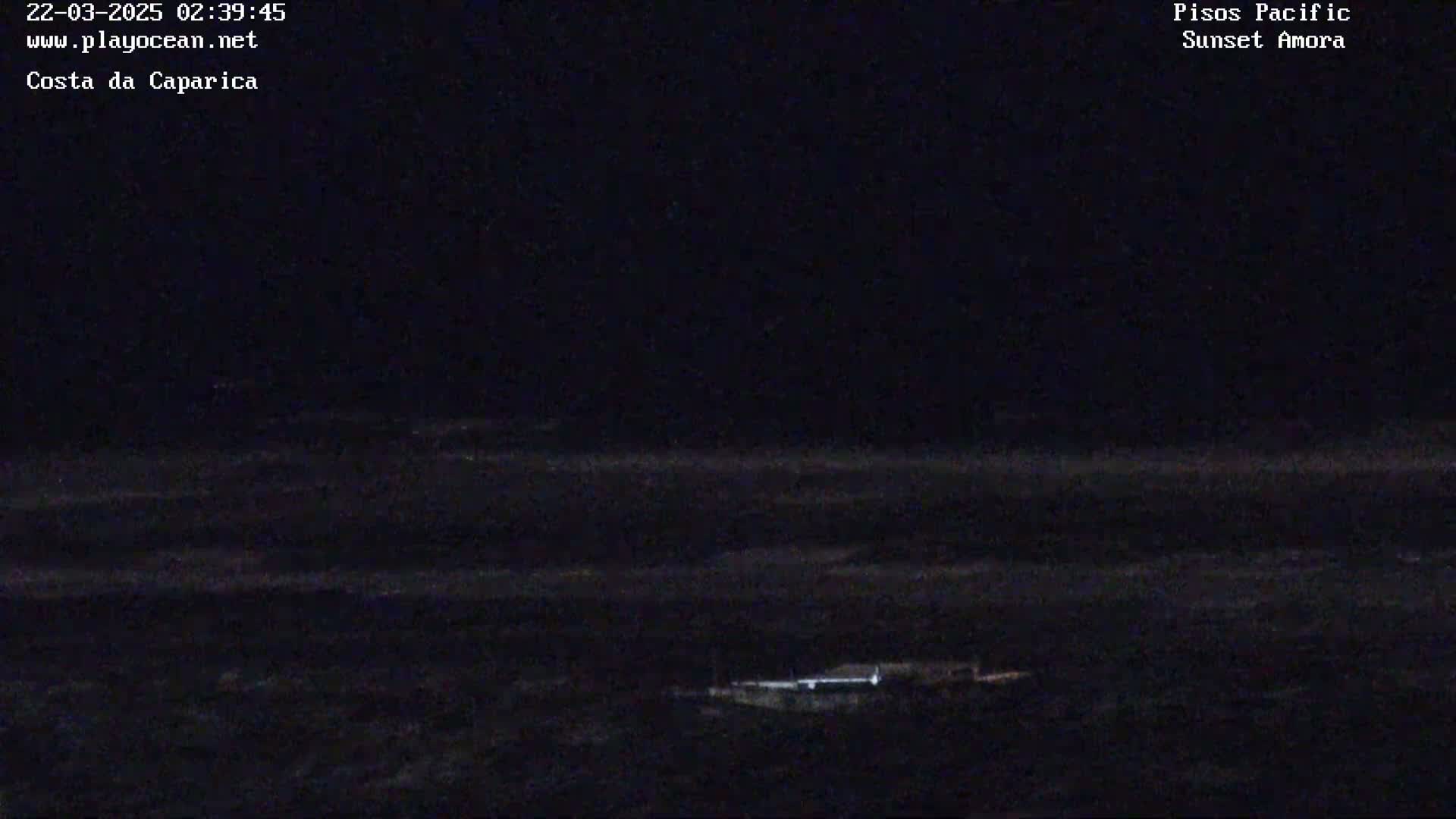 A dark, nighttime view of a calm body of water with a faintly lit structure visible near the bottom.