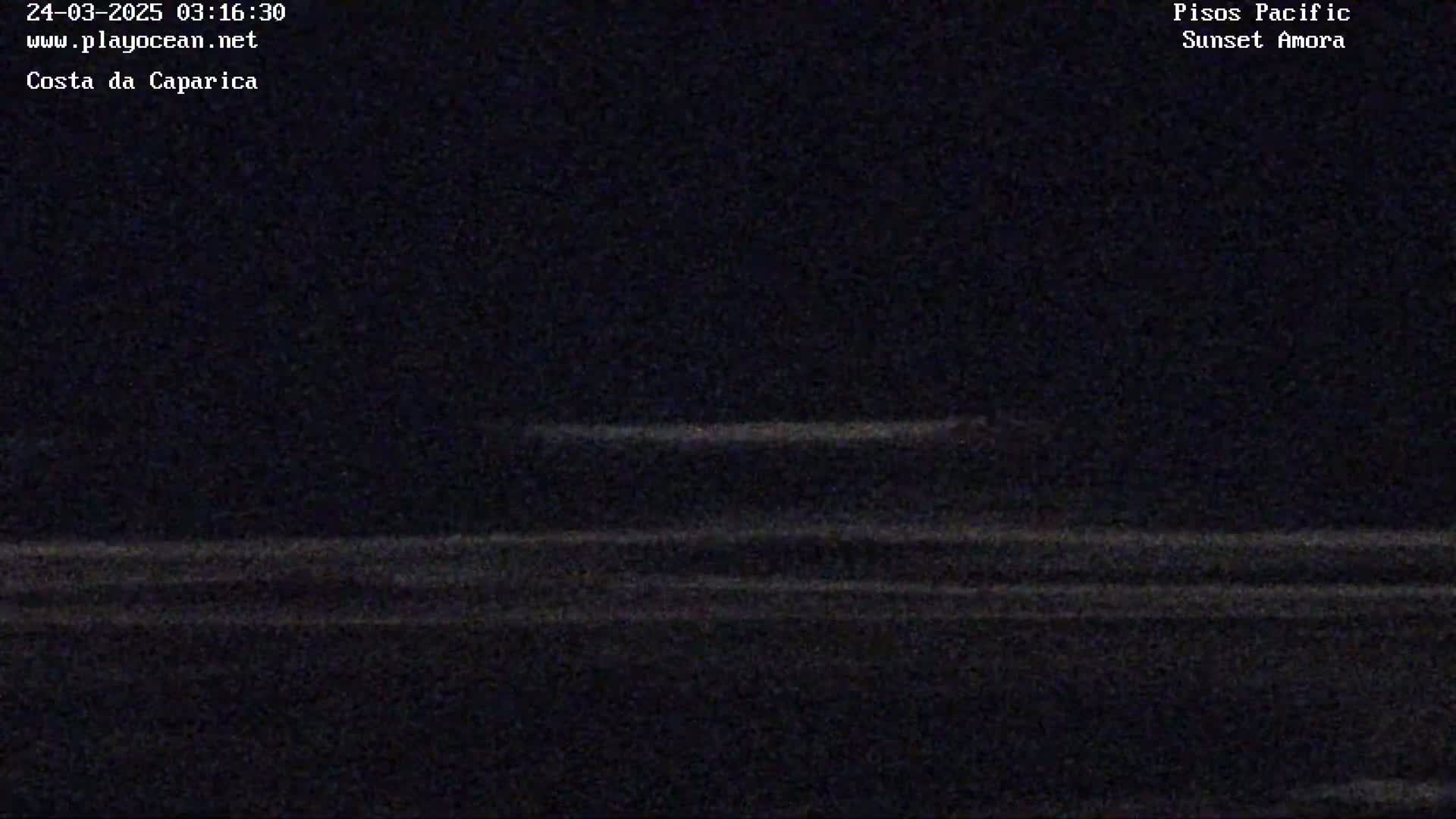 A dark, nighttime image shows a faint, horizontal line representing the ocean near a shoreline.