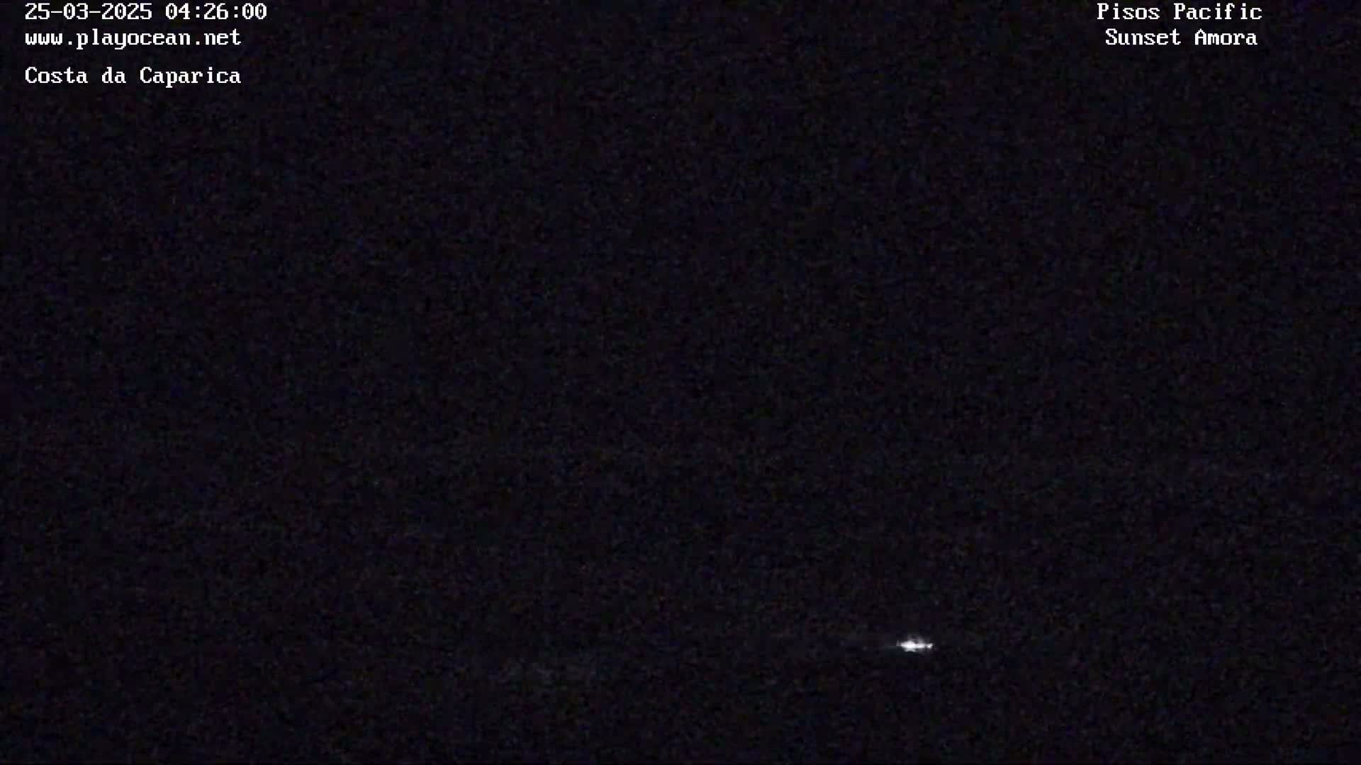 A nighttime, low-light image shows a faint light source on the horizon.