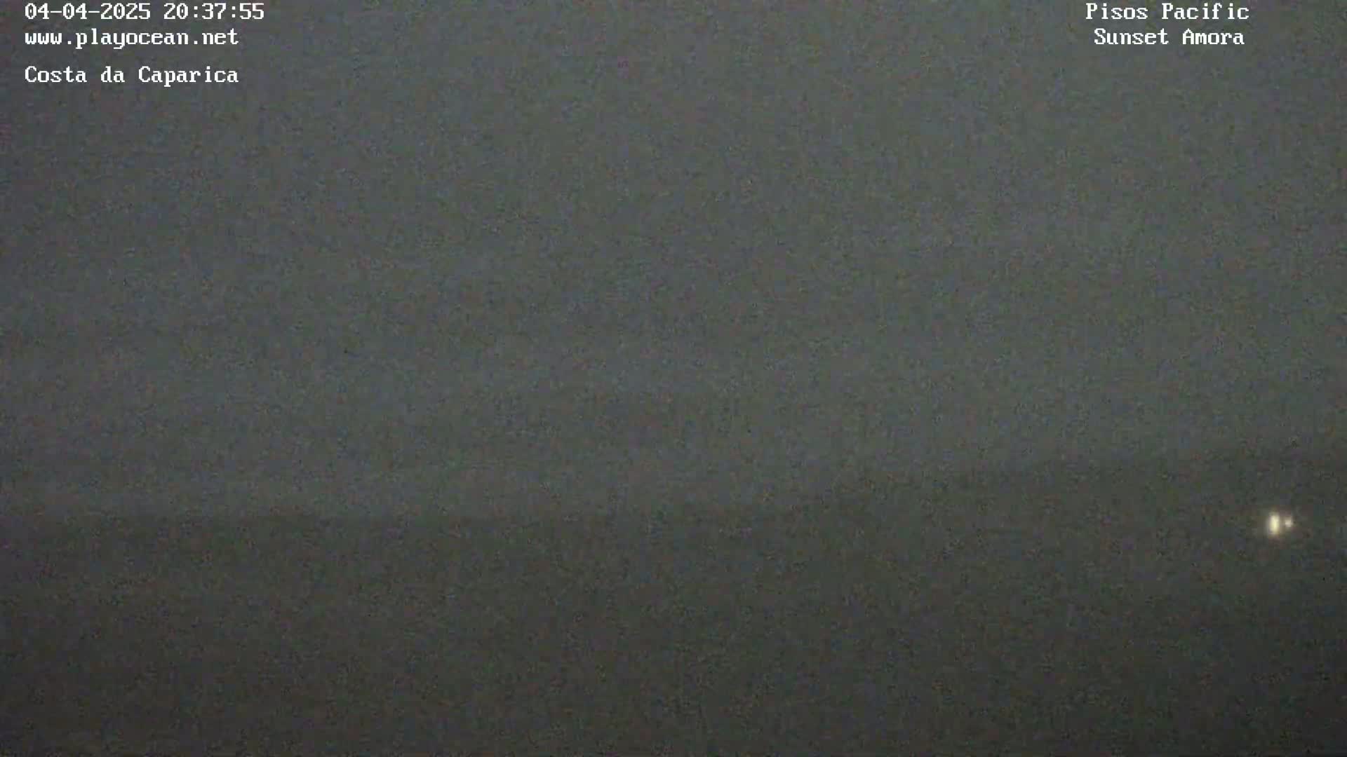 A dark, blurry image shows a mostly featureless landscape under a dark, overcast sky, with a faint light source visible in the far distance.