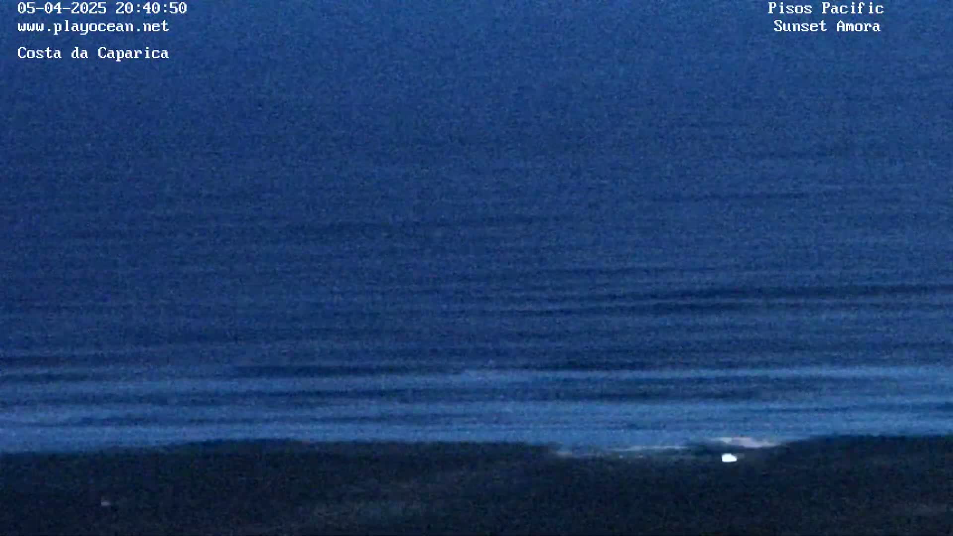 A dark blue ocean with small waves is visible under a twilight sky.
