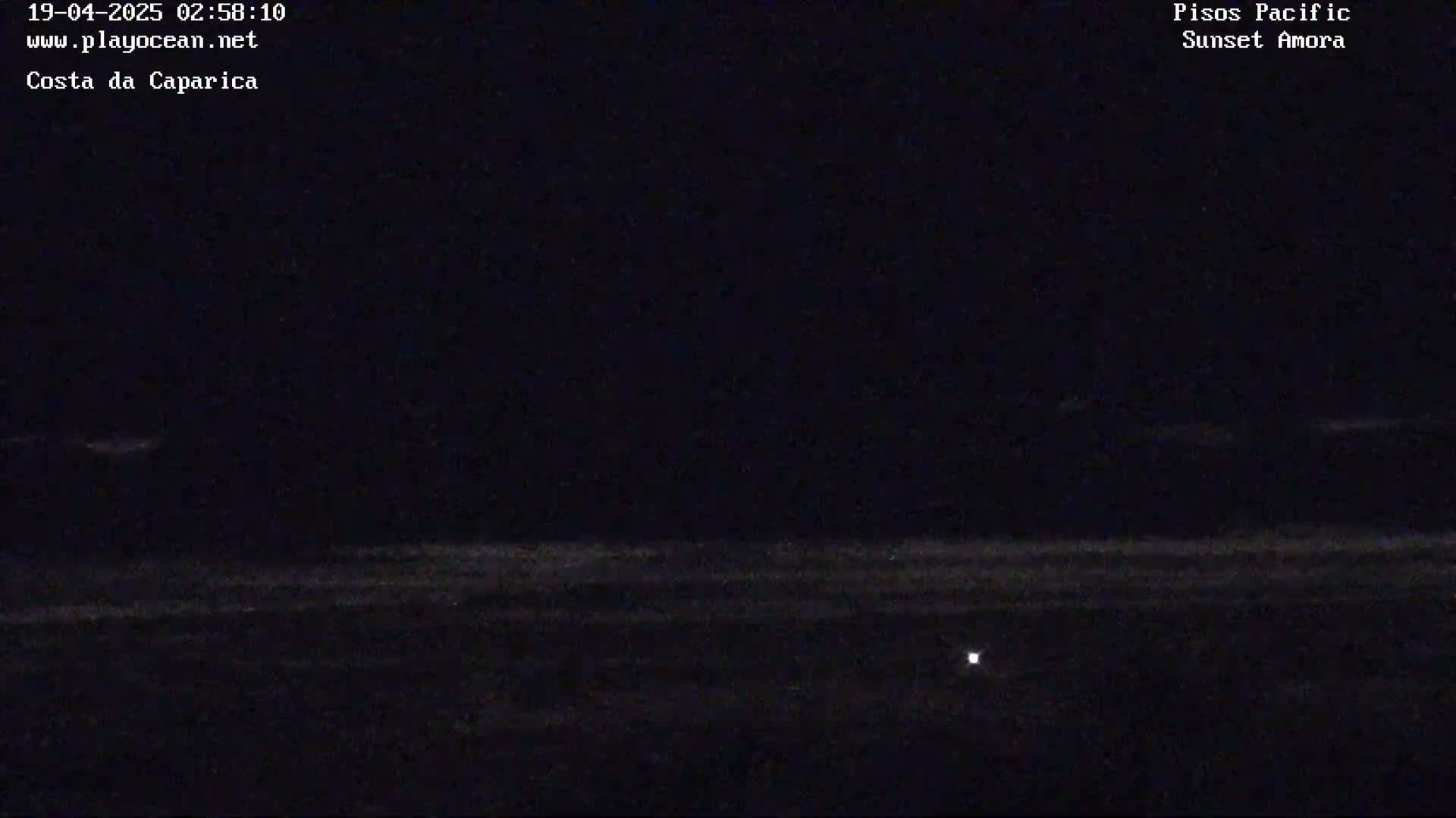 A dark, nighttime beach scene shows a faint horizon line and a single small light source in the bottom-center.