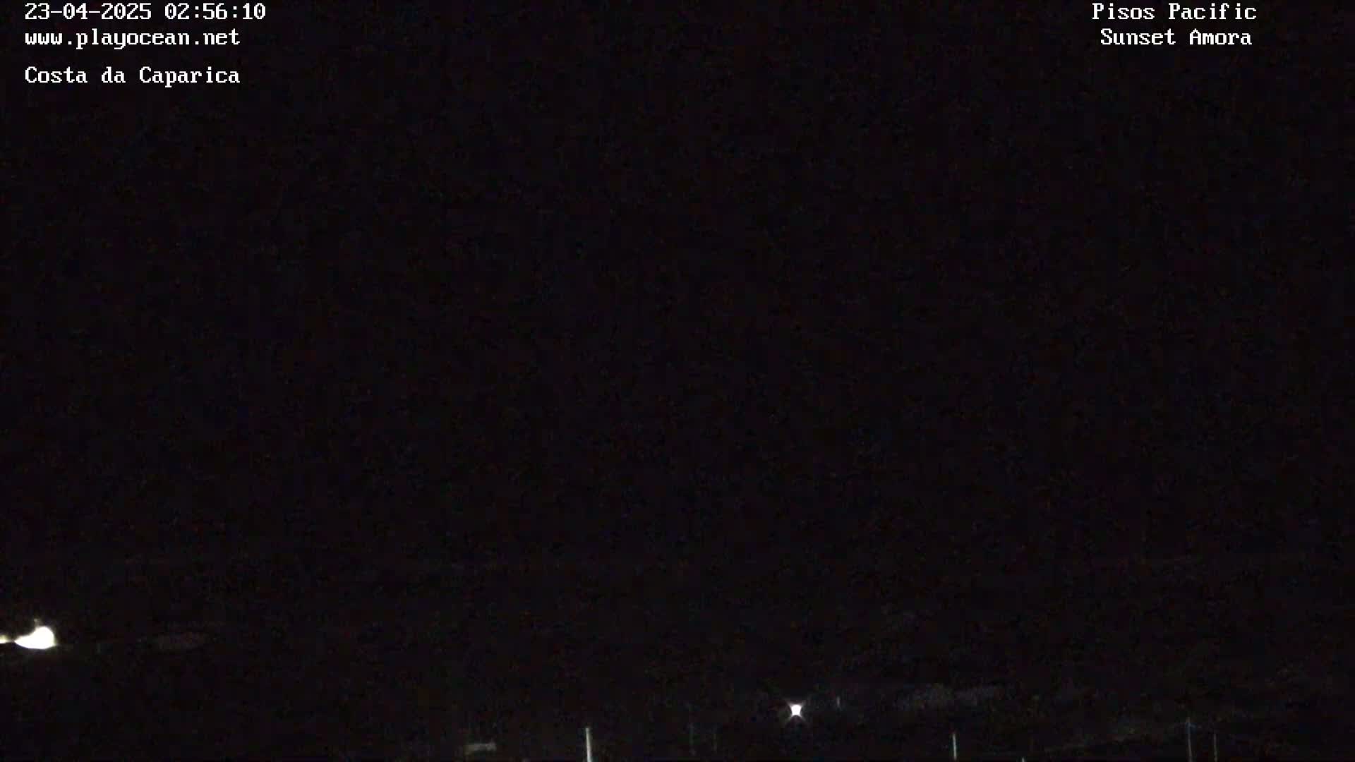A nighttime, dark outdoor scene shows a mostly clear sky with faint lights visible on the horizon.