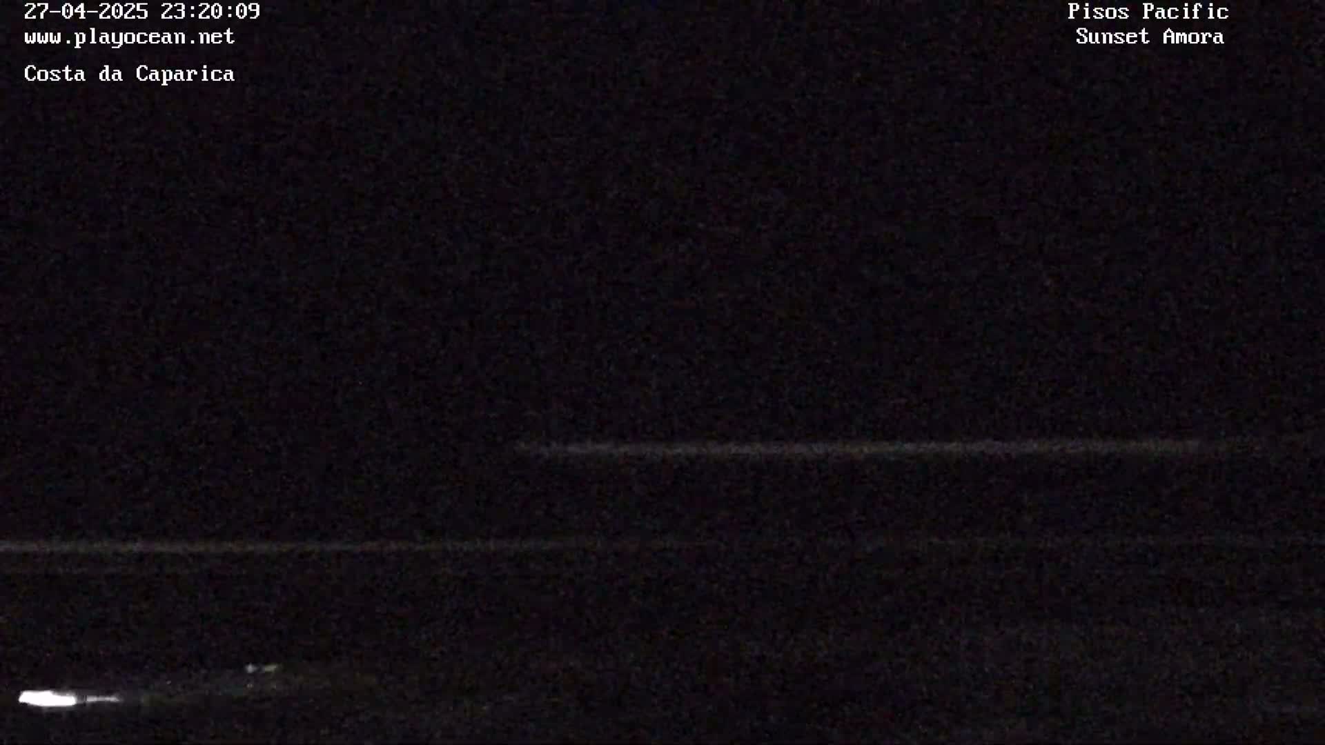A dark nighttime image shows a faint, horizontal line representing the ocean horizon under a clear, dark sky.