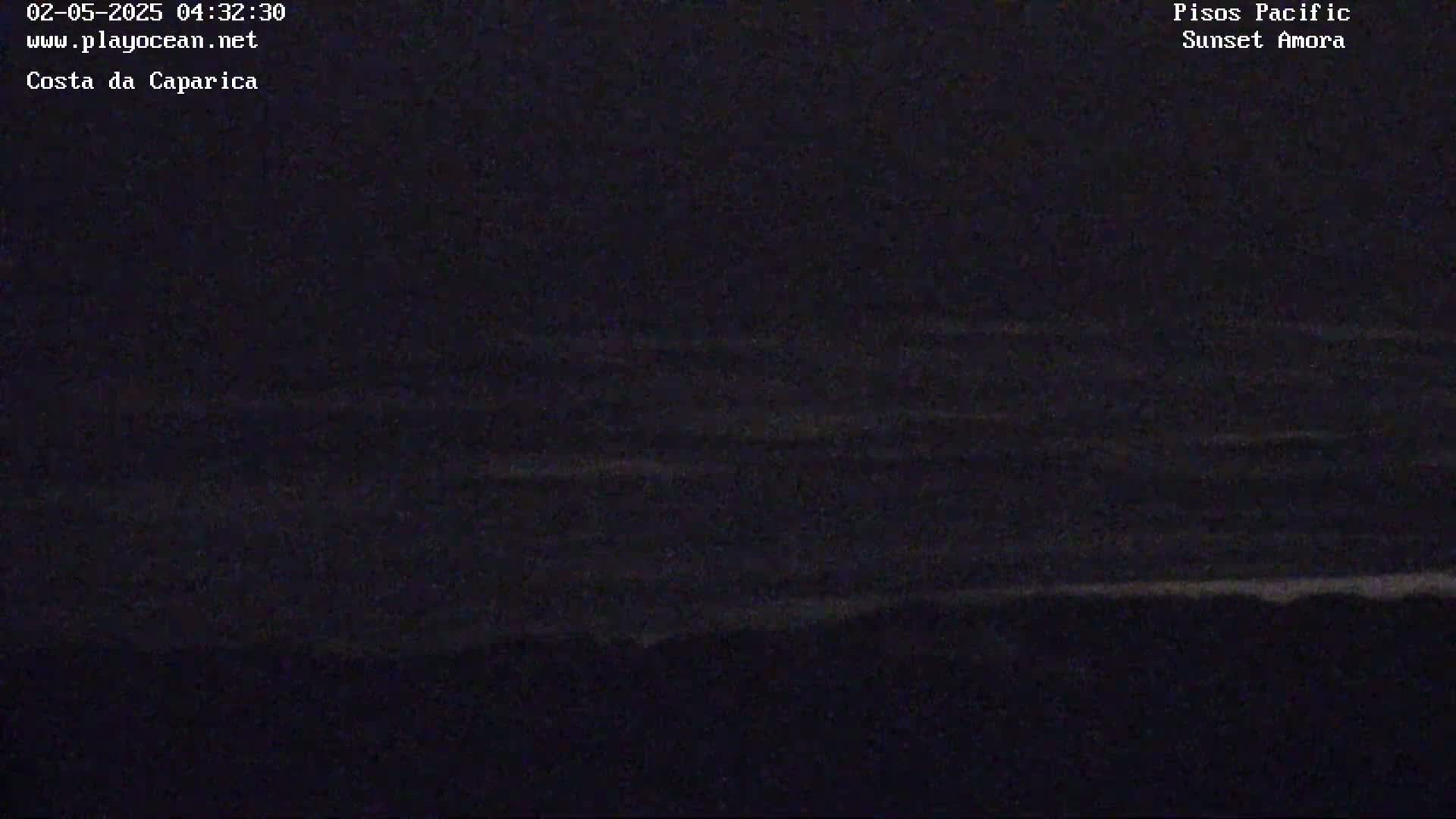 A dark, nighttime ocean with small waves is visible, the shoreline barely discernible in the low light.