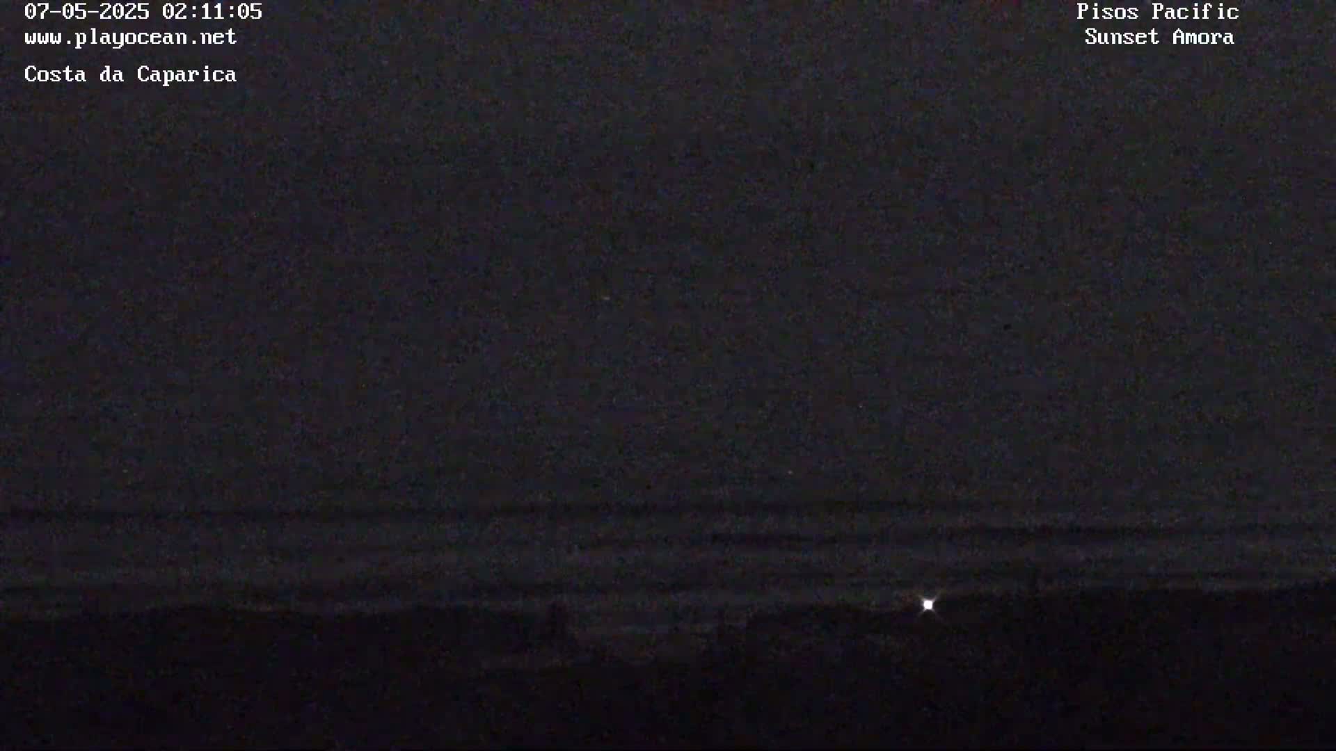 A dark, nighttime view of a calm ocean under a mostly clear sky.