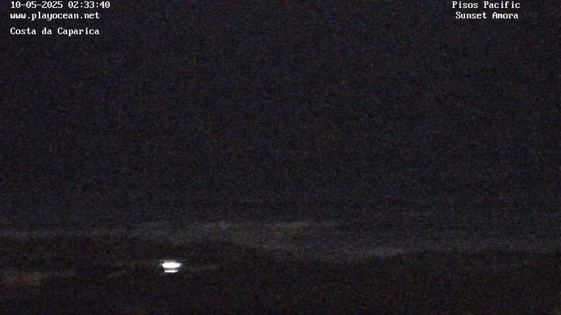 A dark, nighttime image shows a dimly lit horizon line, possibly over water.