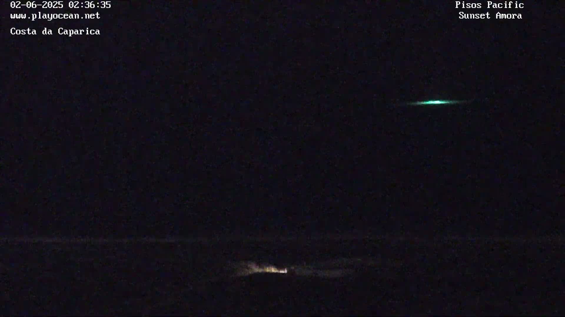 A nighttime, dark ocean scene with a faint green light on the horizon and a small, dim light source near the bottom.