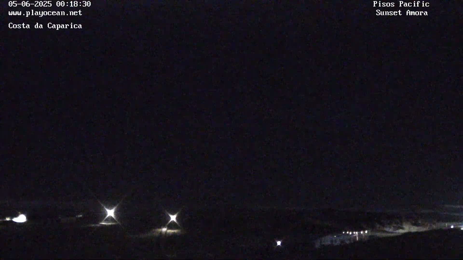 A nighttime, dark view of a landscape with a few distant lights visible.