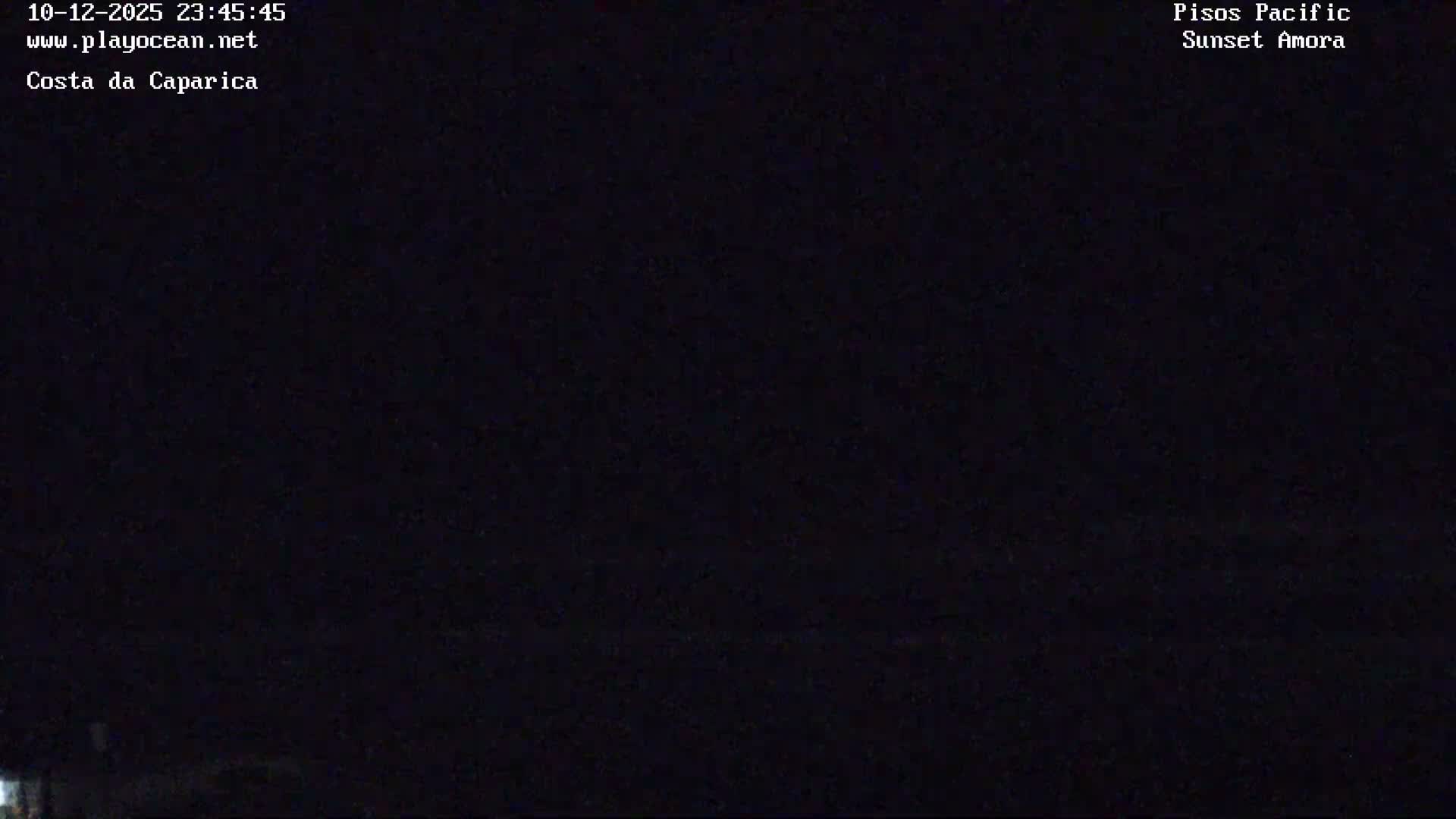 The image displays a nearly pitch-black outdoor scene at night, with only a faint, unidentifiable light source visible at the bottom left, and no discernible weather conditions.