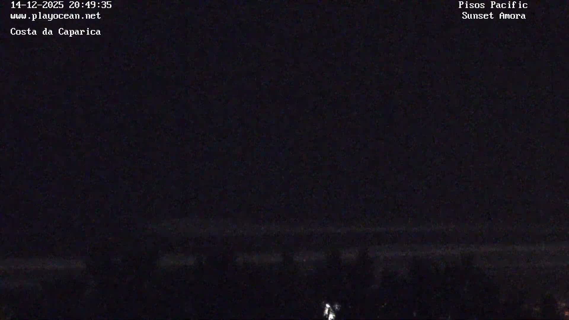 The image displays a nearly pitch-black outdoor scene at night, with only a faint, unidentifiable light source visible at the bottom left, and no discernible weather conditions.