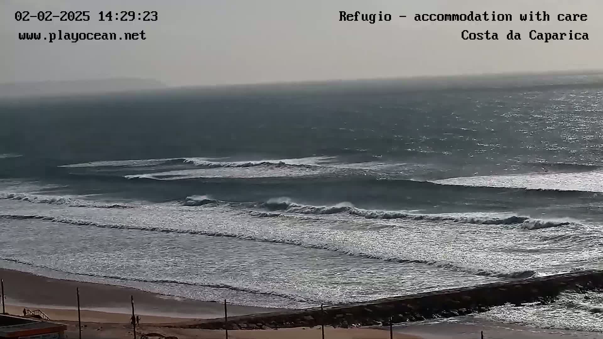 Ocean waves roll onto a sandy beach under an overcast sky.