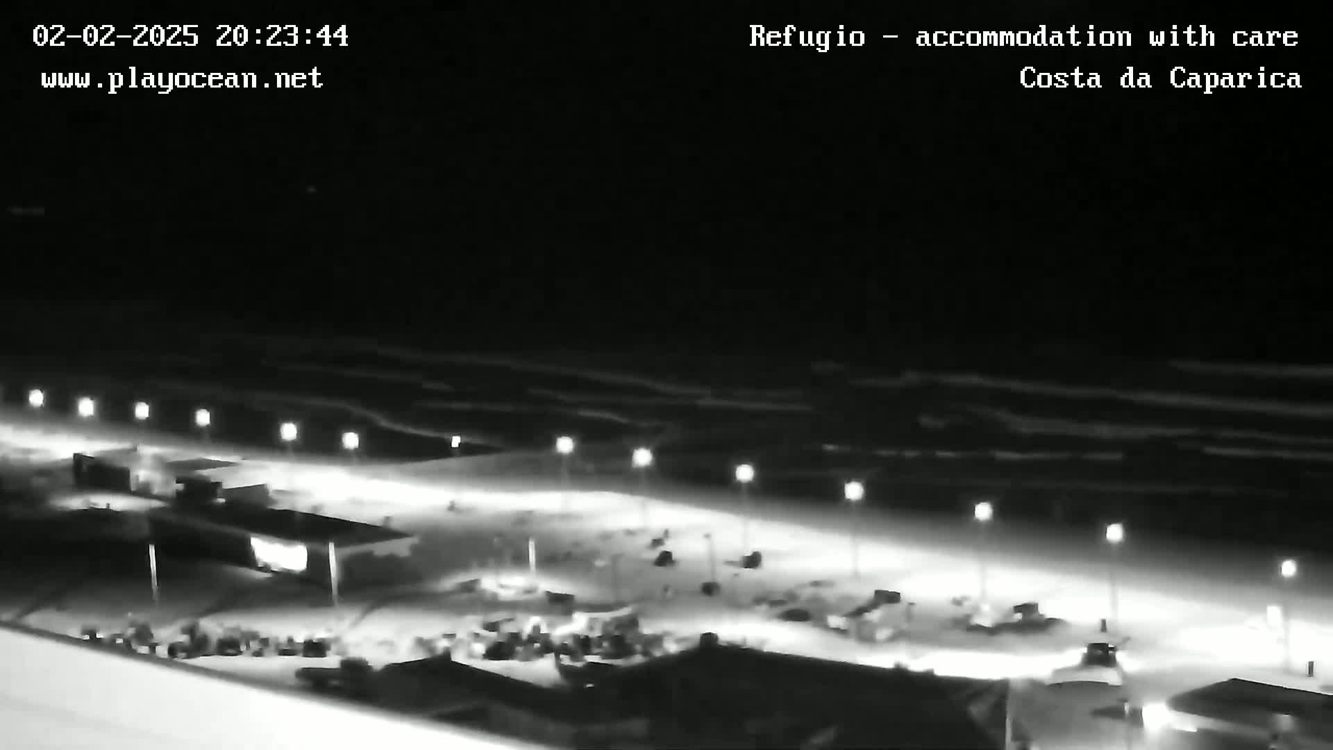 A nighttime view of a beach at night with gently lapping waves under a dark sky.